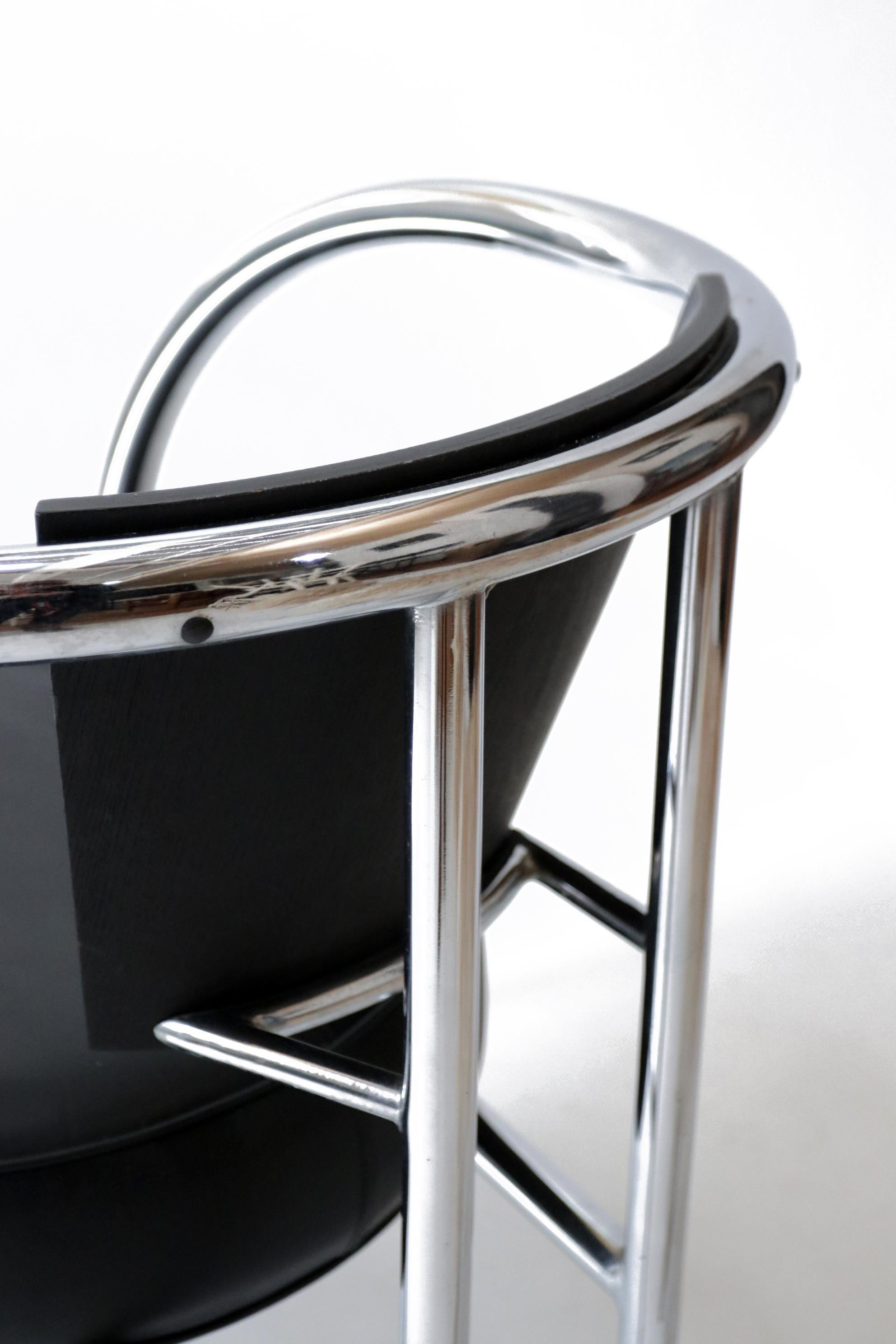 Beautiful 1980s design armchair made of thick chromed tubular frame, black leather seat and curved wooden back. 
Most likely made in Italy.