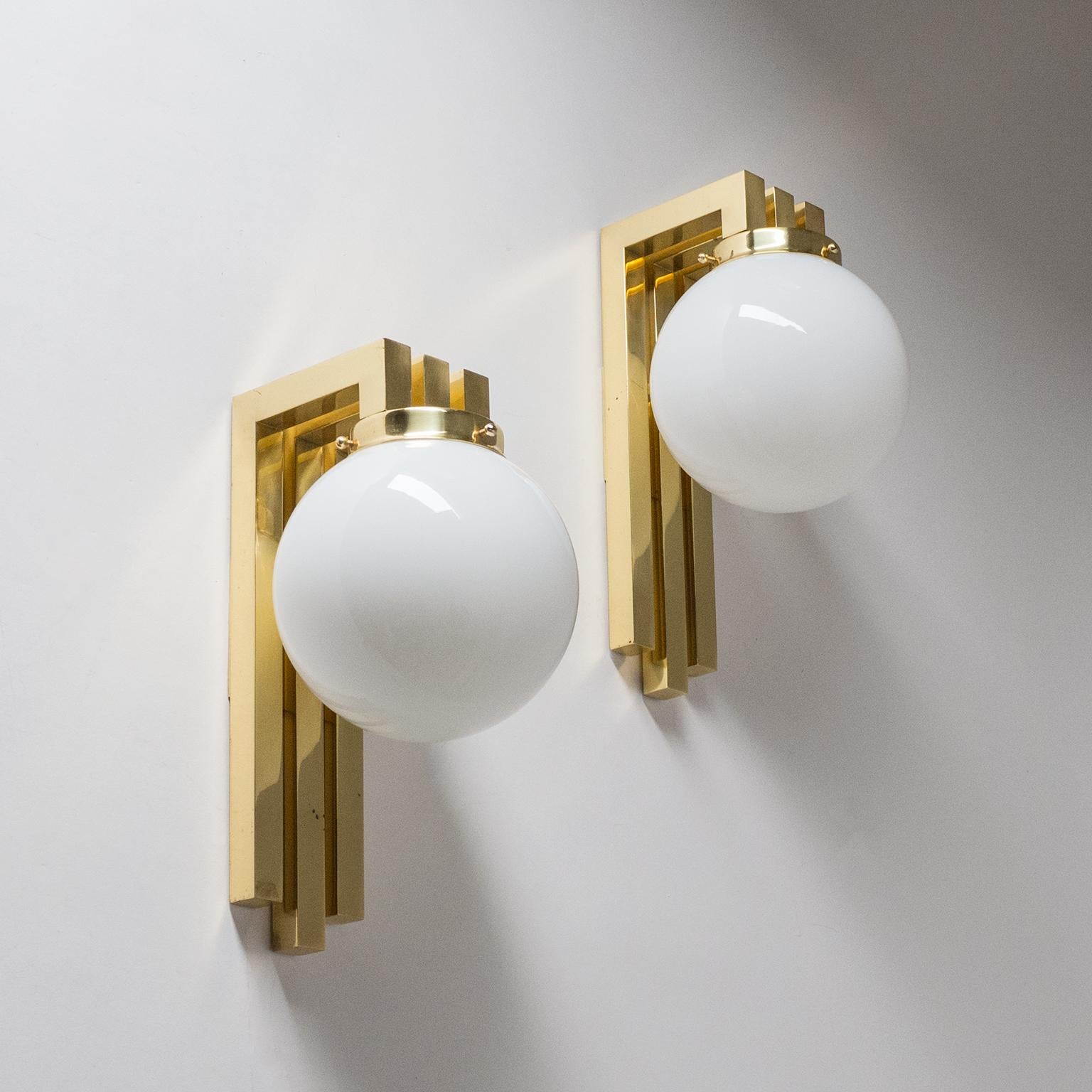 Pair of 1980s Italian brass wall lights with opaline glass diffusers. Very geometric rendering reminiscent of Romeo Rega designs, but also of Wiener Werkstätte and Art Deco. Minor patina on the brass. Each light has one E27 socket.