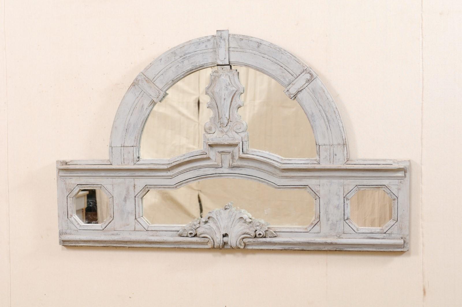 An Italian fragment panel, which would make a great small headboard, from the 19th century. This antique architectural panel features a rectangular-shaped lower frame, with geometrically carved windows and curling leaf carving at bottom center,