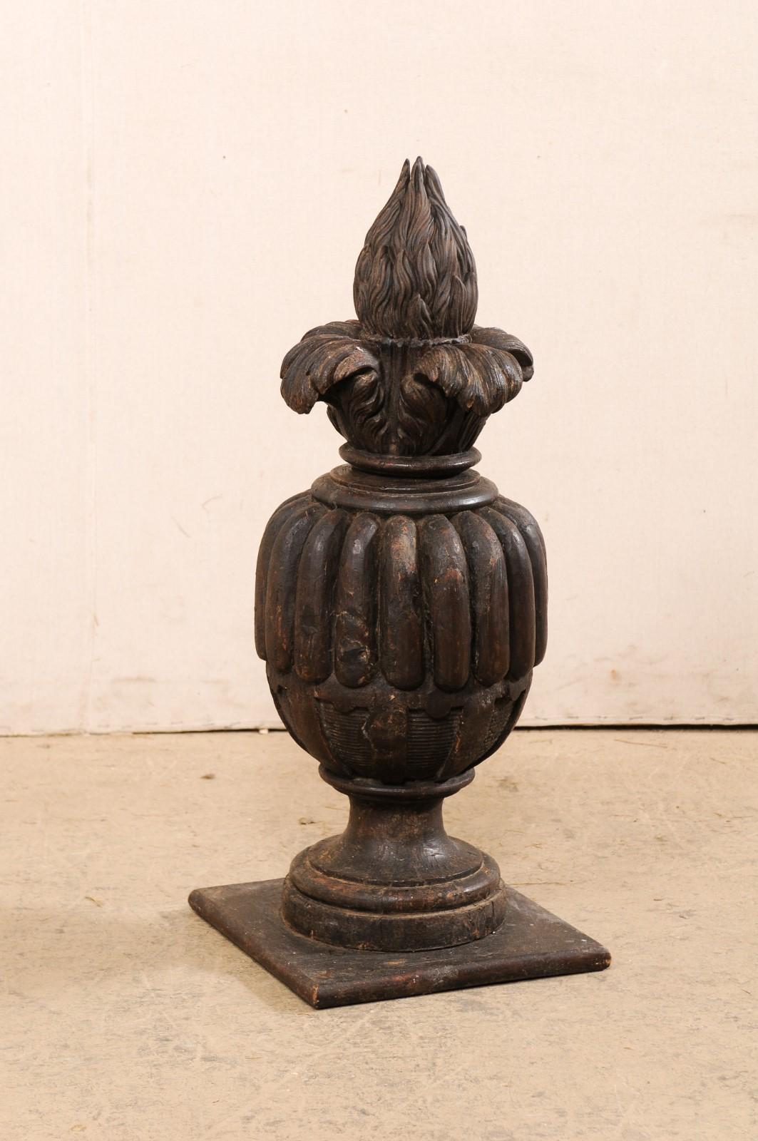 An Italian carved-wood finial from the 19th century. This antique finial from Italy, standing approximately 2.75 feet in height, has an urn-shaped center carved with thickly reeded perimeter, acanthus and fire projecting from its topside, and