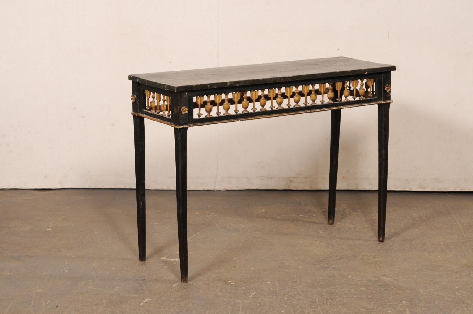 An Italian carved wood console table, with its original painted finish, from the 19th century. This antique table from Italy has a slender, rectangular top over an apron with beautifully pierce-carved repeating arrow and urn motif about three sides,