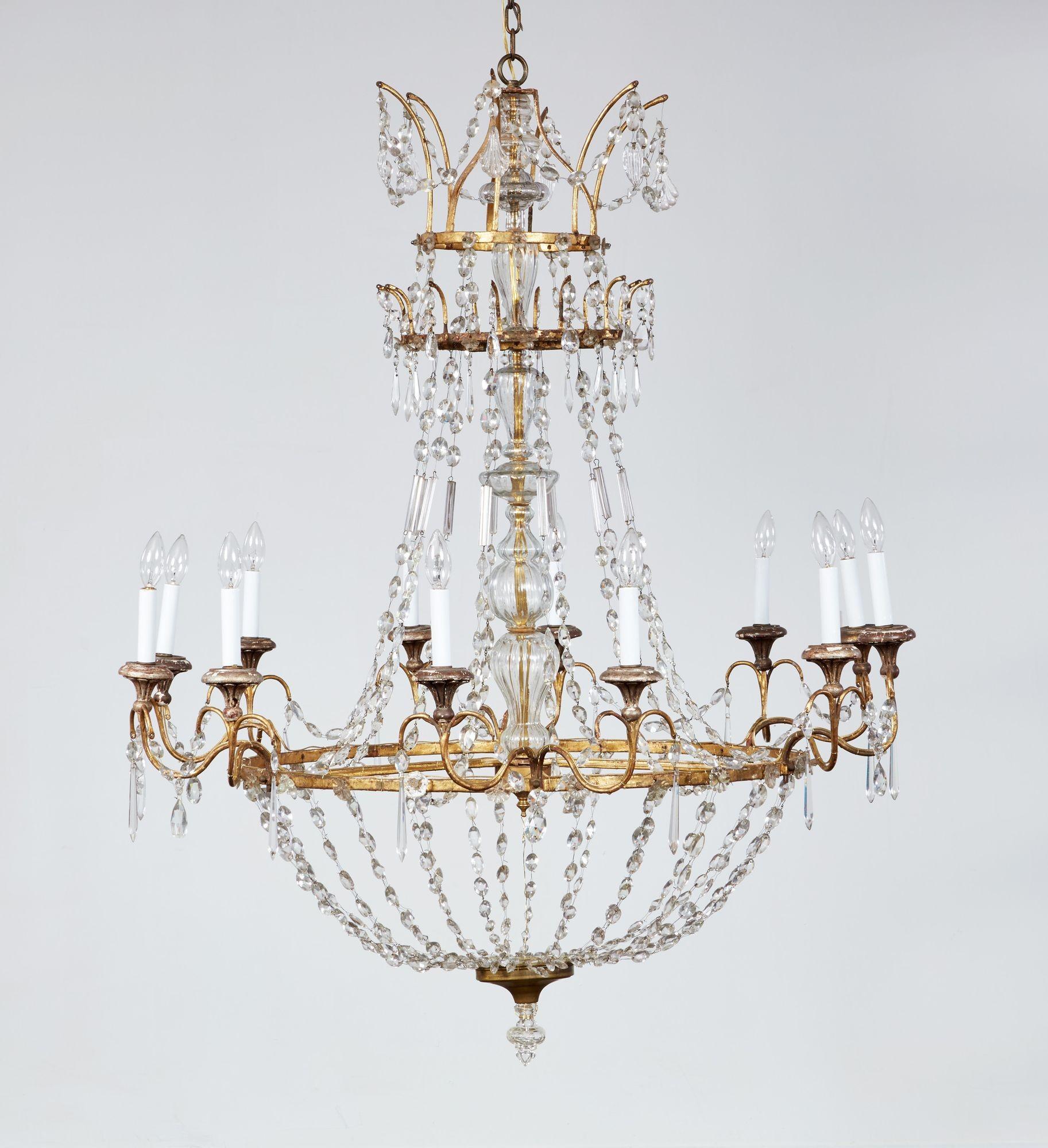 Splendido lampadario italiano di inizio Ottocento in legno dorato, ferro dorato, argento dorato e cristallo di dimensioni considerevoli, con la classica forma ad anello e a cesto con dodici luci e con la colonna centrale in vetro a segmenti, la