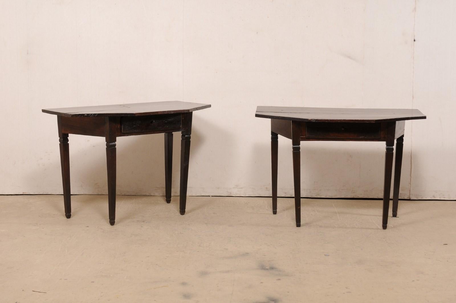 An Italian pair of carved-wood demi-lune tables from the 19th century. This antique pair of tables from Italy each feature a halved-octagon shaped top, atop an inset apron which houses a drawer at front side, and is canted at flanking sides. The