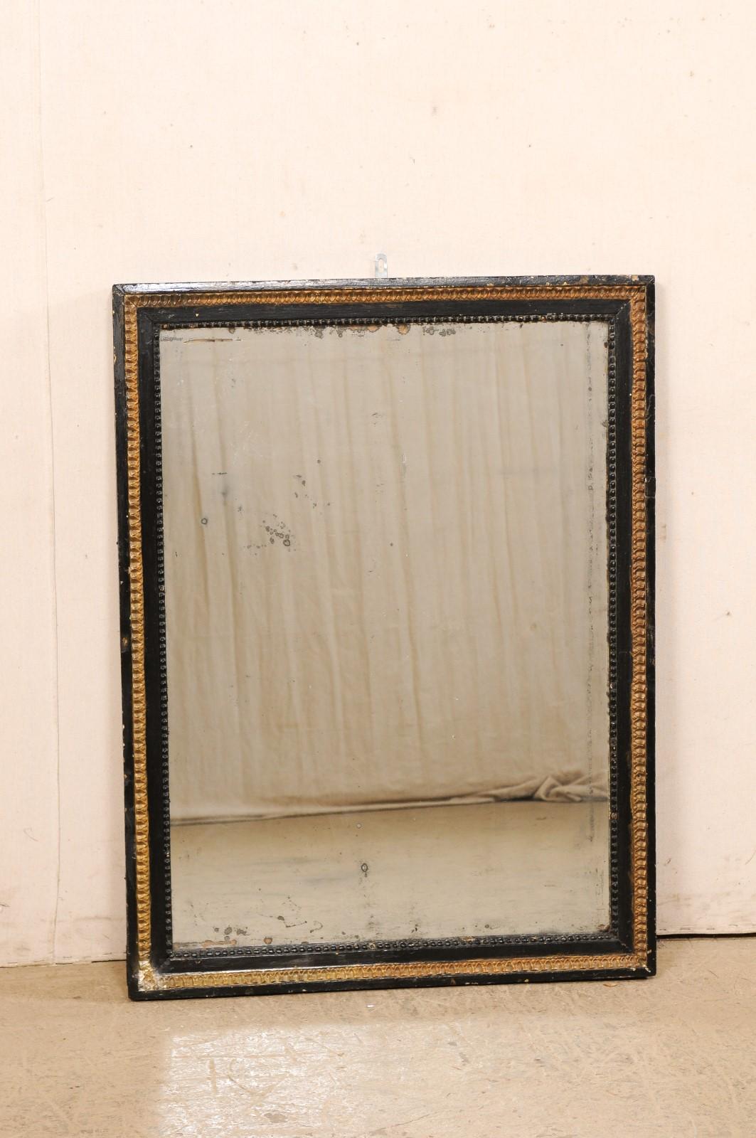 An Italian painted-wood wall mirror from the 19th century. This antique mirror from Italy is rectangular-shaped with a cleanly molded-wood outer surround, with petite bead trim lining the inner edge of mirror, and lamb's tongue trim just before the