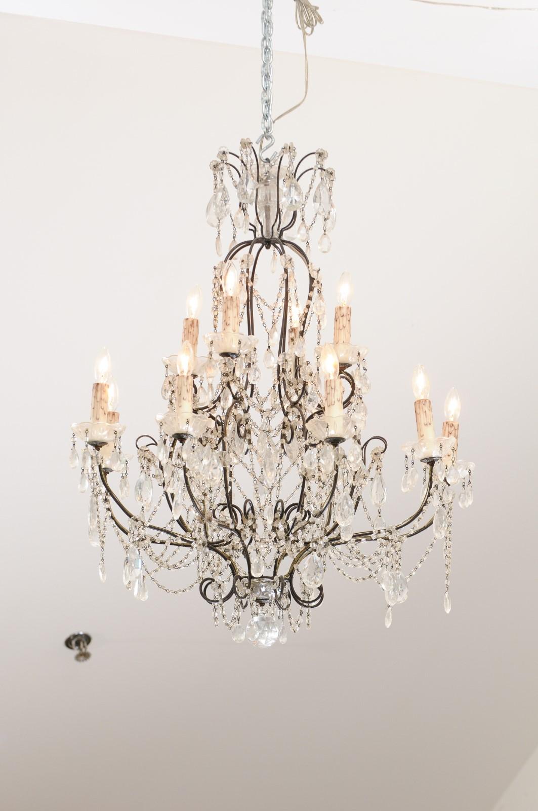 An Italian 10-light crystal chandelier from the 19th century, with iron armature and scrolling arms. Created in Italy during the 19th century, this chandelier features an iron structure supporting faceted crystals and rosettes connected to one