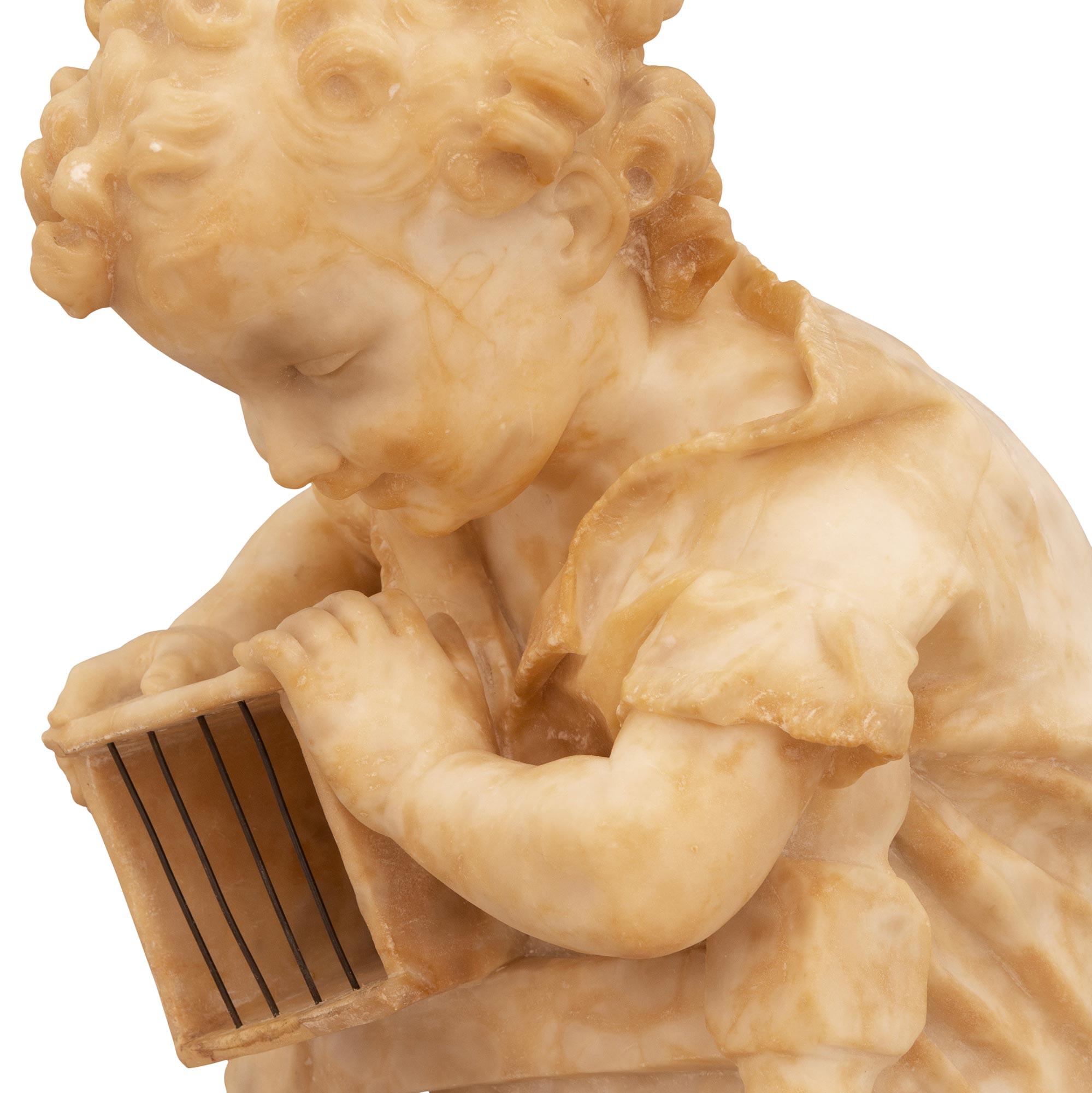 A most charming Italian 19th century Alabaster statue of a boy and his cat. The intricately detailed statue depicts a young boy mischievously playing with his cat by luring it with a mouse in a box. The boy is standing and leaning over the back of