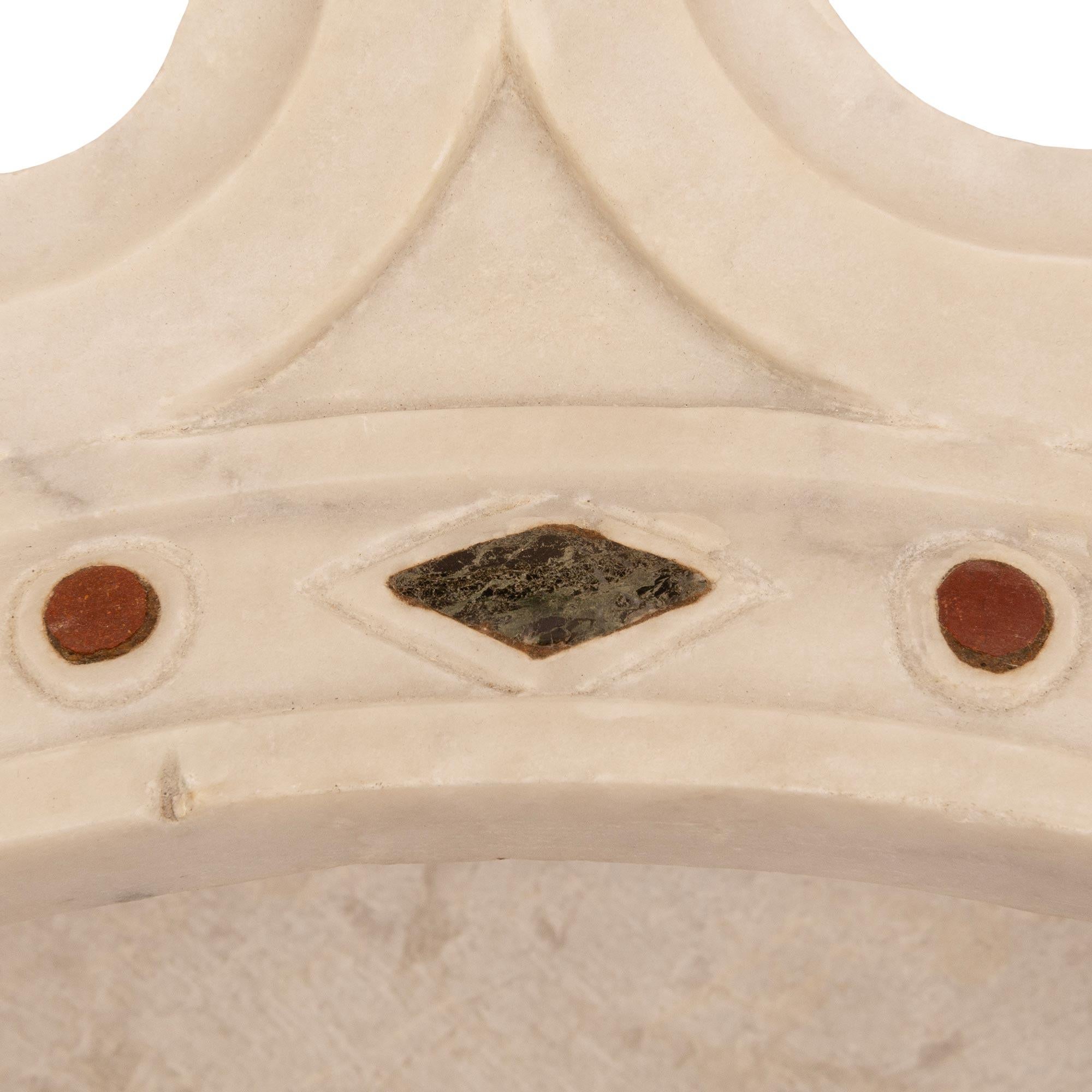 A beautiful and most decorative Italian 19th century architectural wall element of a crown. The white Carrara marble crown is jeweled with other marble inlays of Vert de Patricia, Sienna and Rosso Marbles. The peeks of the crown showcase a wonderful
