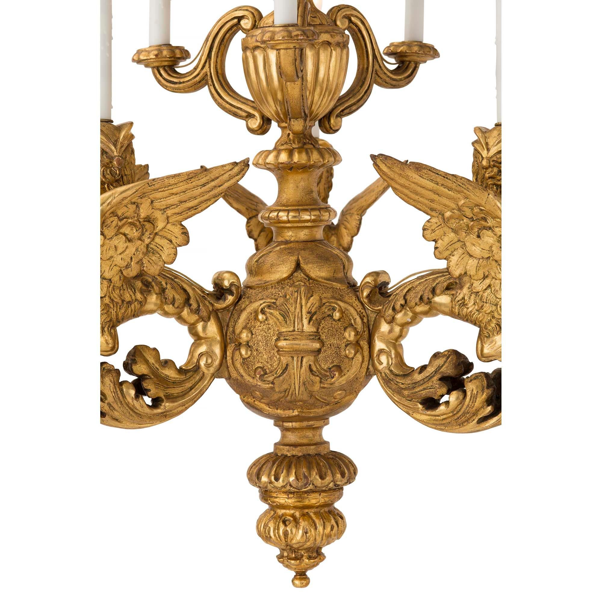 A high quality and extremely decorative early 19th century Italian Baroque giltwood chandelier. The chandelier with three different levels of lights has ten electrified arms. The bottom finial with carved foliate designs is below a large ball with
