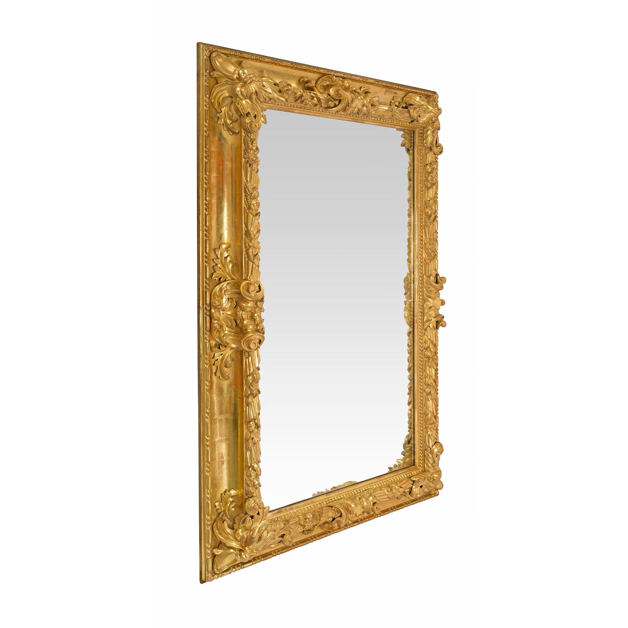 A handsome Italian 19th century Baroque giltwood mirror. The central mirror plate is framed within a fine beaded band and richly carved foliate designs. At the center of each side is a beautiful and finely carved scrolled foliate reserve and a most