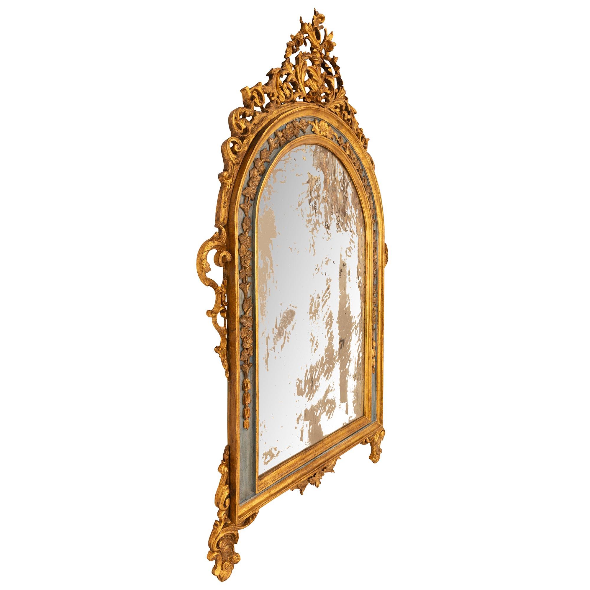 Miroir baroque italien du 19e siècle en bois doré et bois patiné, très décoratif et impressionnant. Ce magnifique miroir, avec sa plaque d'origine, est centré par un fleuron inférieur en forme d'arbalète à motifs feuillagés, flanqué de montures