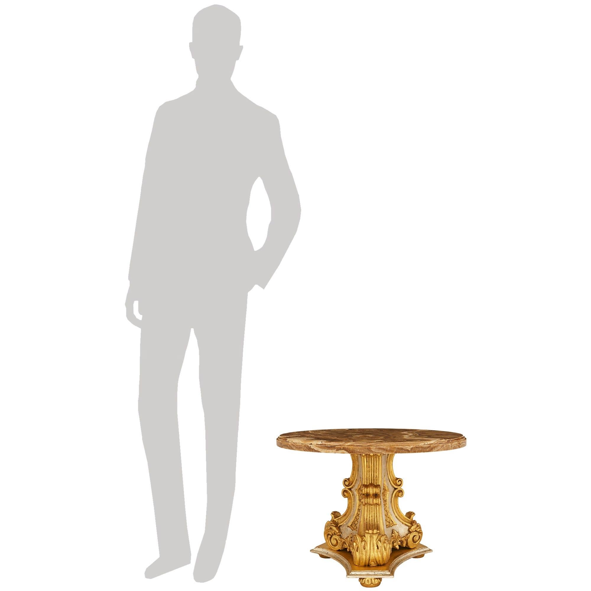 Très élégante table basse en bois doré, méca et onyx Alabastro Fiorito de style baroque italien du XIXe siècle. Cette superbe table est surélevée par trois pieds en bois doré sous une base triangulaire en Mecca bicolore. Au-dessus, un trio de