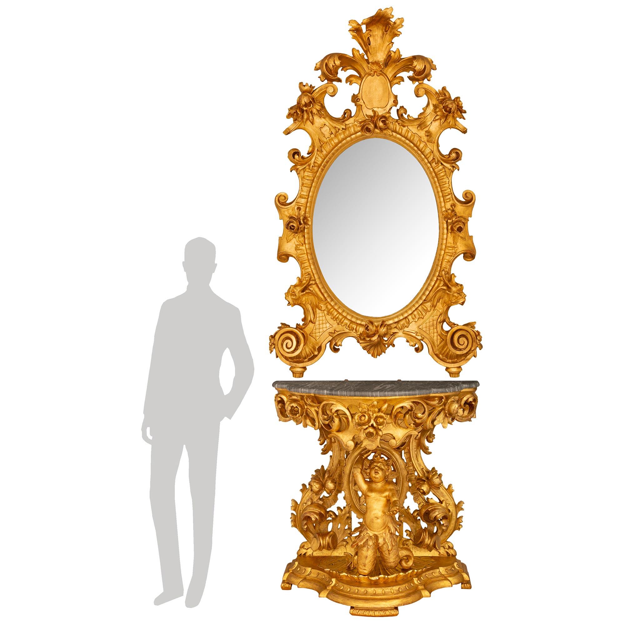 A palatially scaled and high quality Italian 19th century Baroque st. Giltwood and Gris St. Anne marble matching console and mirror. The stately oval shaped mirror with its original mirror plate has two elaborate scrolls at the bottom corners that