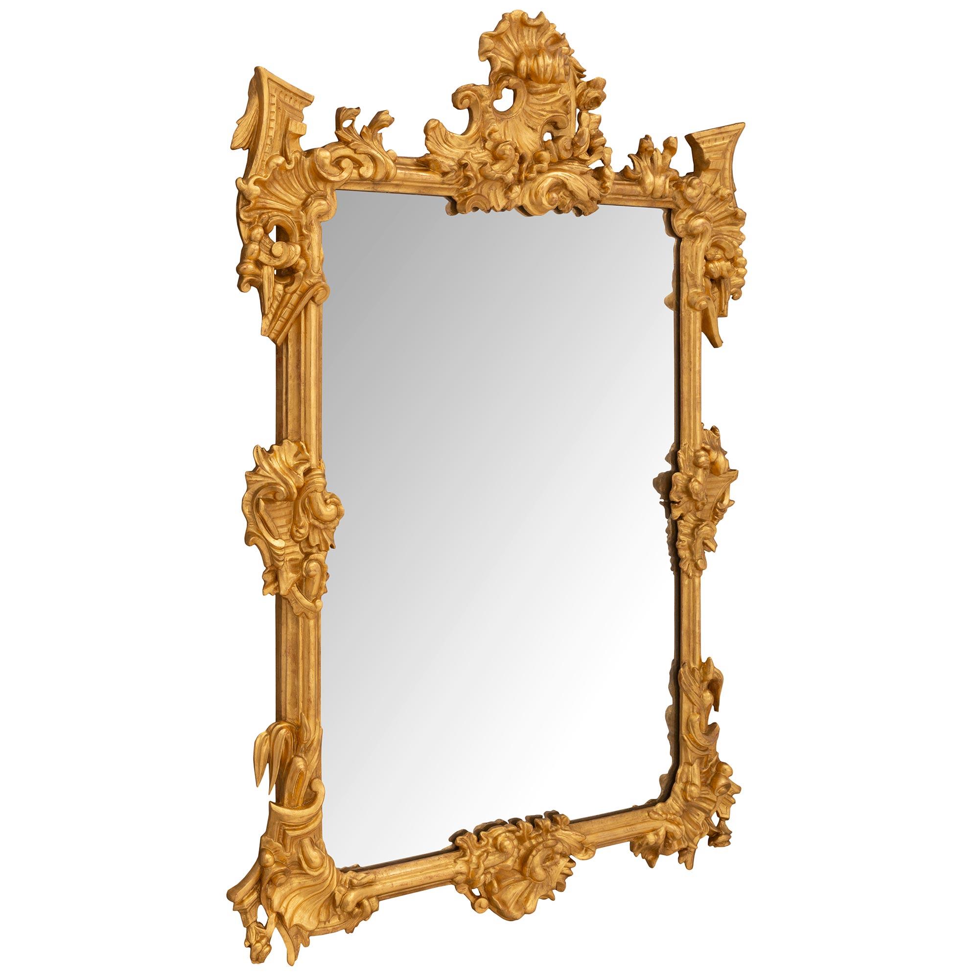 A stunning Italian 19th century Baroque st. giltwood mirror. The original mirror plate is set within an elegant mottled border which extends throughout the frame. At each corner are striking richly carved pierced foliate reserves with additional