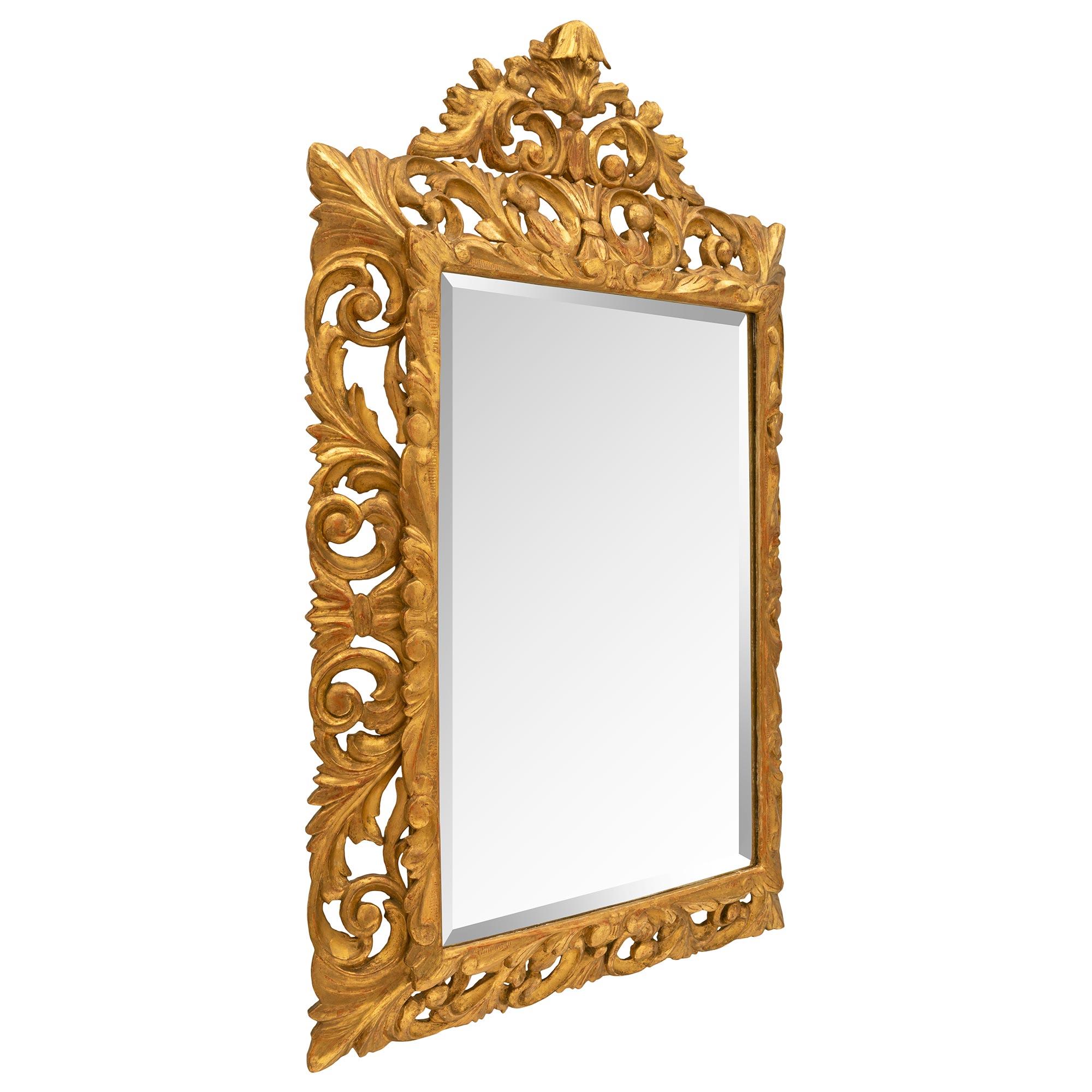 Un beau miroir baroque italien du 19ème siècle en bois doré. Le miroir conserve sa plaque biseautée d'origine, enchâssée dans une fine bordure mouchetée aux motifs gravés. Le cadre ajouré présente un ensemble impressionnant de motifs feuillagés