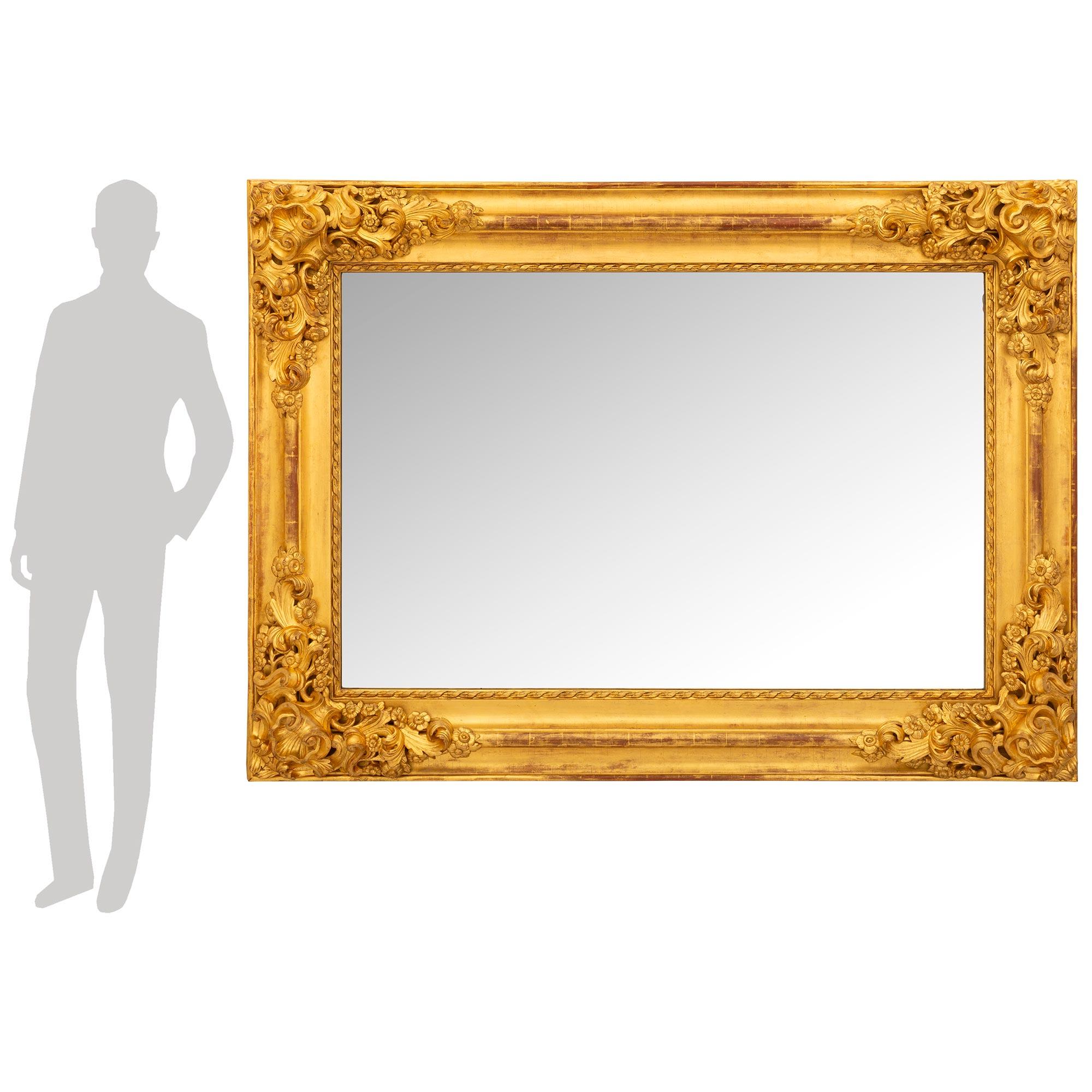 Miroir en bois doré baroque italien du XIXe siècle, impressionnant et de grande qualité. La glace de ce miroir aux dimensions généreuses est encadrée dans un cadre en bois doré richement sculpté, avec des réserves de coquillages à grande échelle