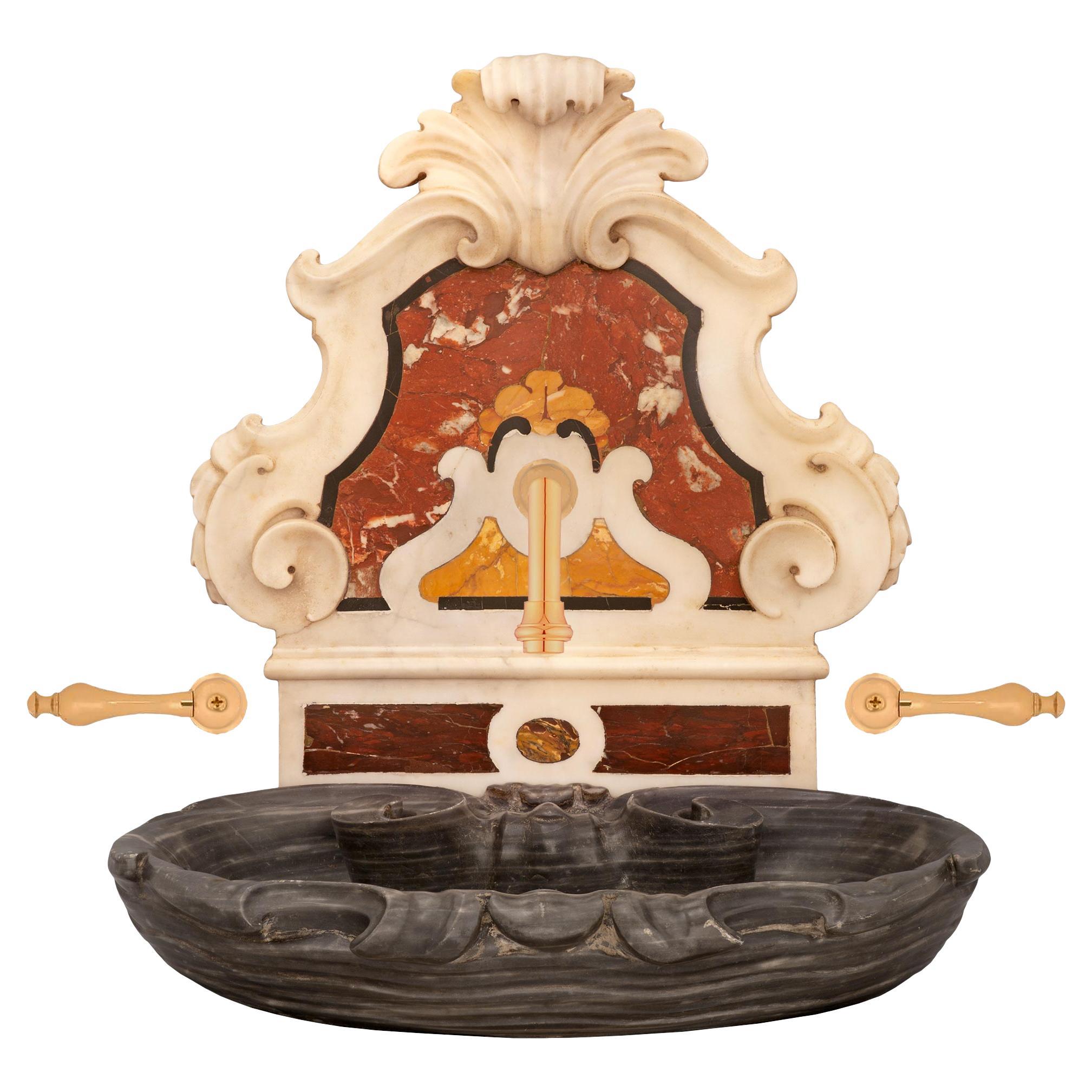 A stunning and extremely decorative Italian 19th century Baroque st. marble basin/fountain. The sink displays a beautiful richly sculpted solid Bleu Turquin marble basin with charming scrolled mottled movements. The backplate displays beautiful