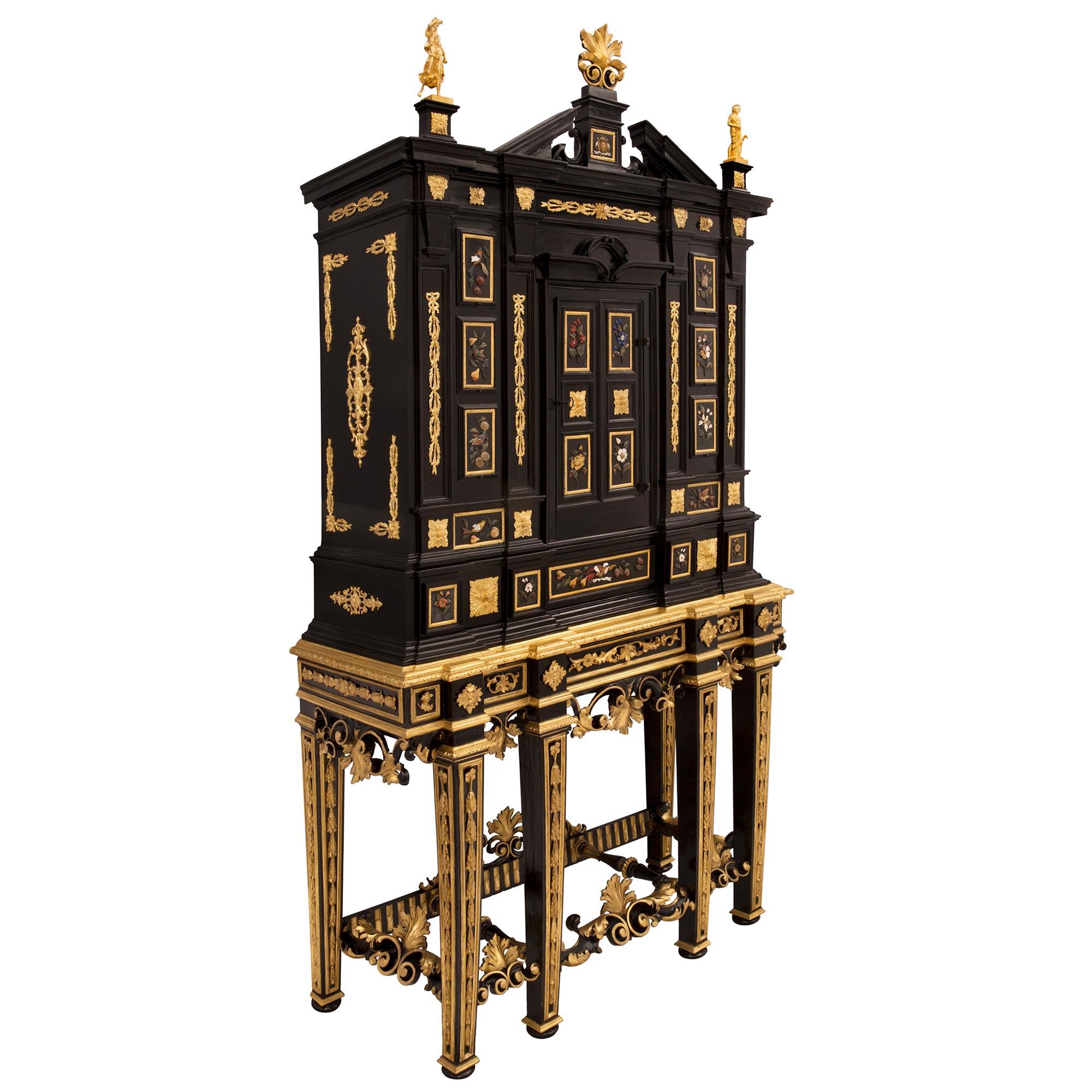 Un superbe cabinet baroque italien du 19e siècle en bois fruitier ébonisé, bois doré, bronze doré et pierres semi précieuses et dures de Florentine. Le meuble est surélevé par une base unique et très décorative composée de six remarquables pieds
