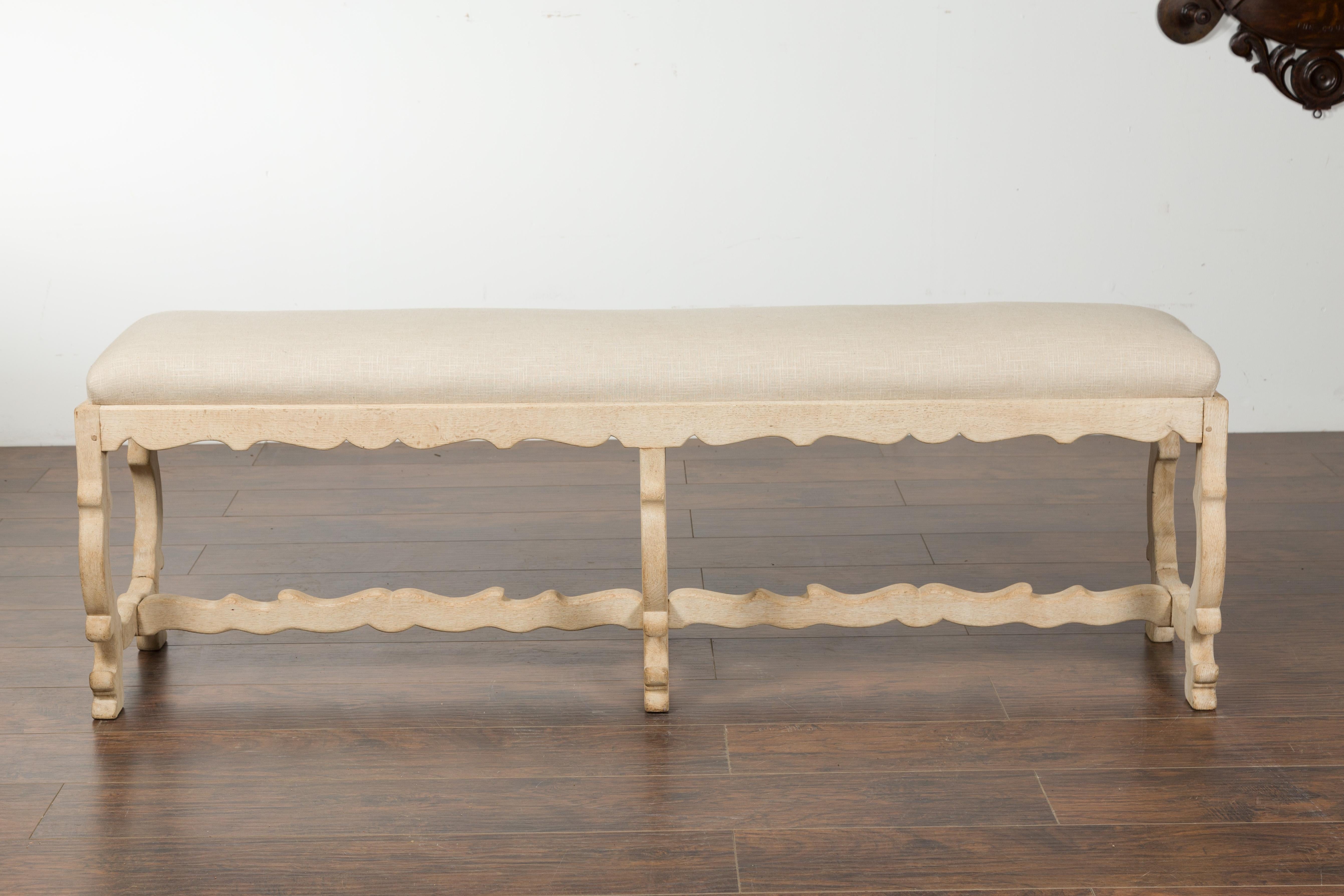 An Italian Baroque style bleached oak bench from the 19th century, with lyre-shaped legs and new upholstery. Created in Italy during the 19th century, this Baroque style oak bench features a long rectangular top newly recovered with a linen fabric.