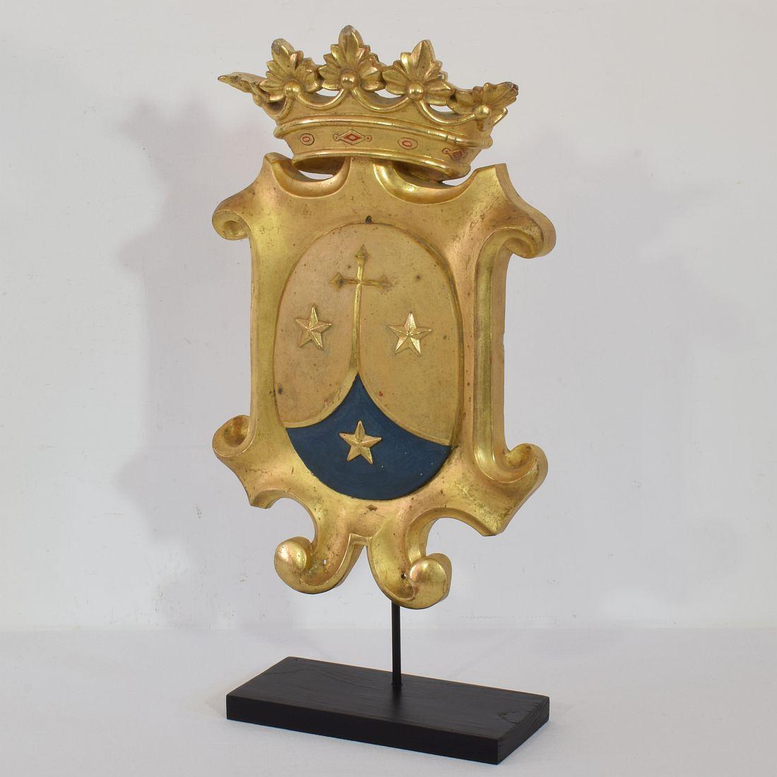 Wonderful handcarved wooden coat of arms with its original gilding, Italy, circa 1850. 
Weathered and small losses. Measurement includes the base.