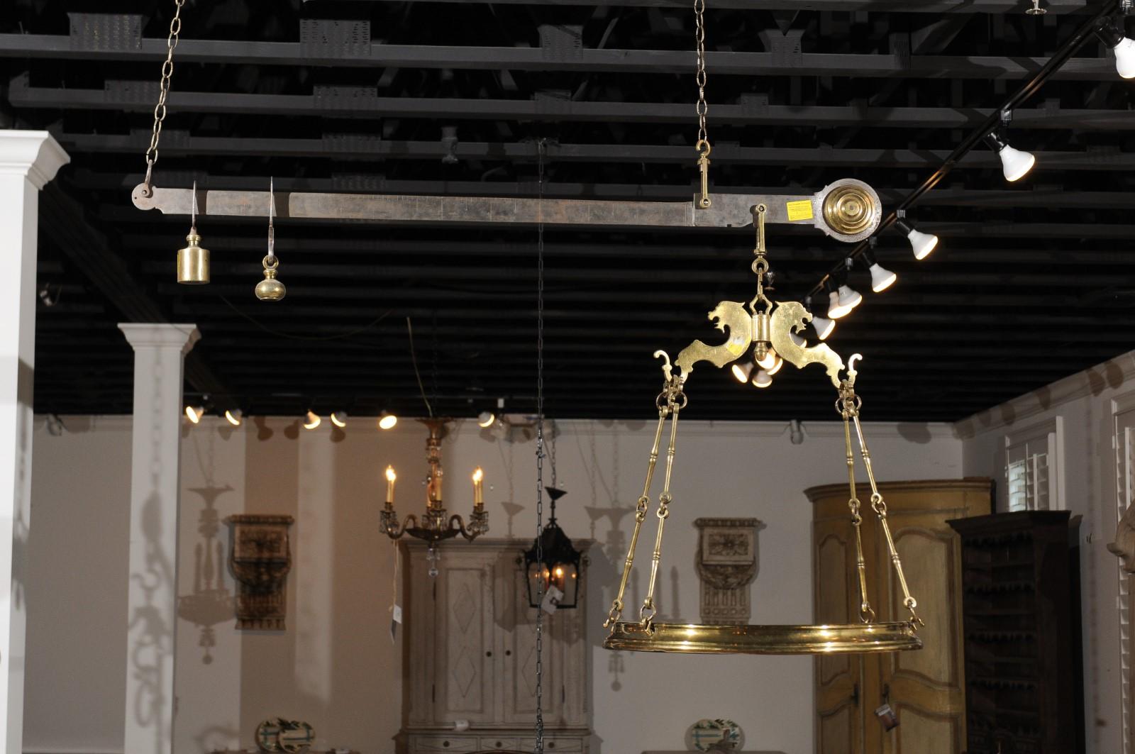 An Italian brass hanging scale for weighing cheese from the 19th century with circular tray. Born in Italy during the 19th century, this brass scale features a horizontal shaft presenting weights at its extremity. A circular tray, measuring 25