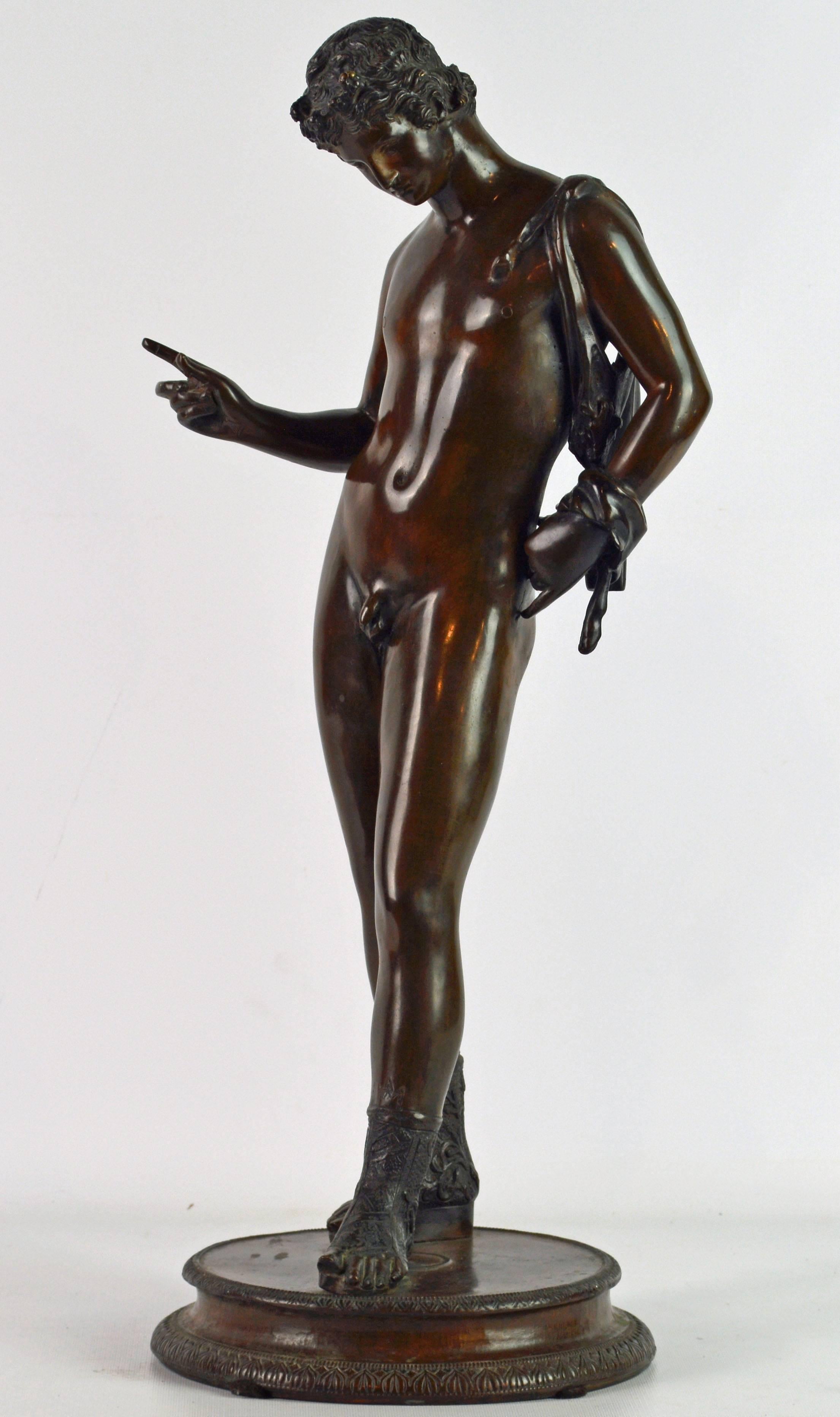 Standing 22 inches tall this patinated bronze statue depicts Antinous who was a close friend or lover og emperor Hadrian. After his untimely death Hadrian deified him. Standing in the nude on a circular base he is wearing a goatskin water container