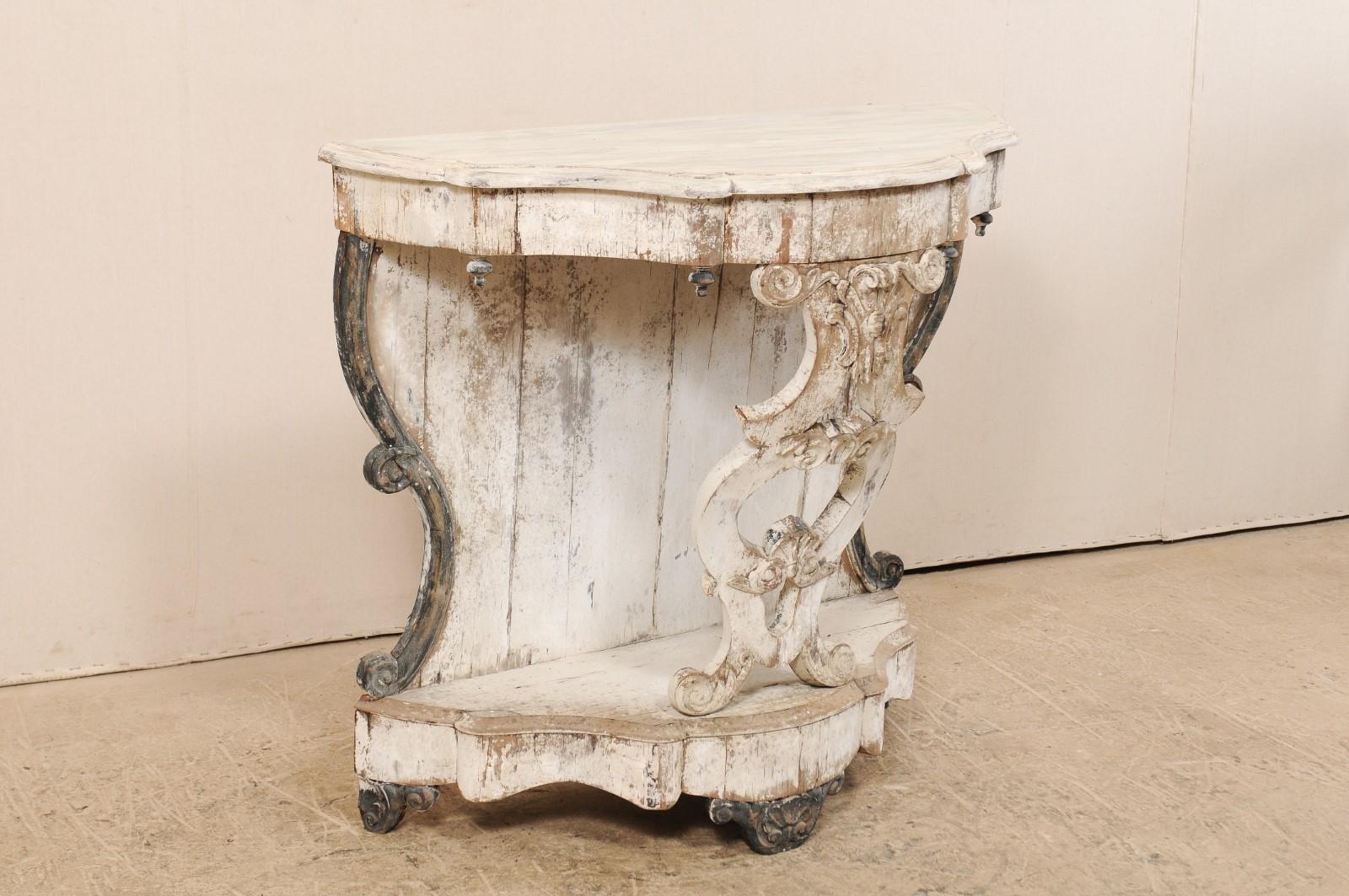An Italian 19th century carved wood Rococo style console table. This gorgeous Italian half-moon shaped wall console table features a beautifully scalloped edge top above a lower bottom base which mimics the same scalloped design about the skirt. The