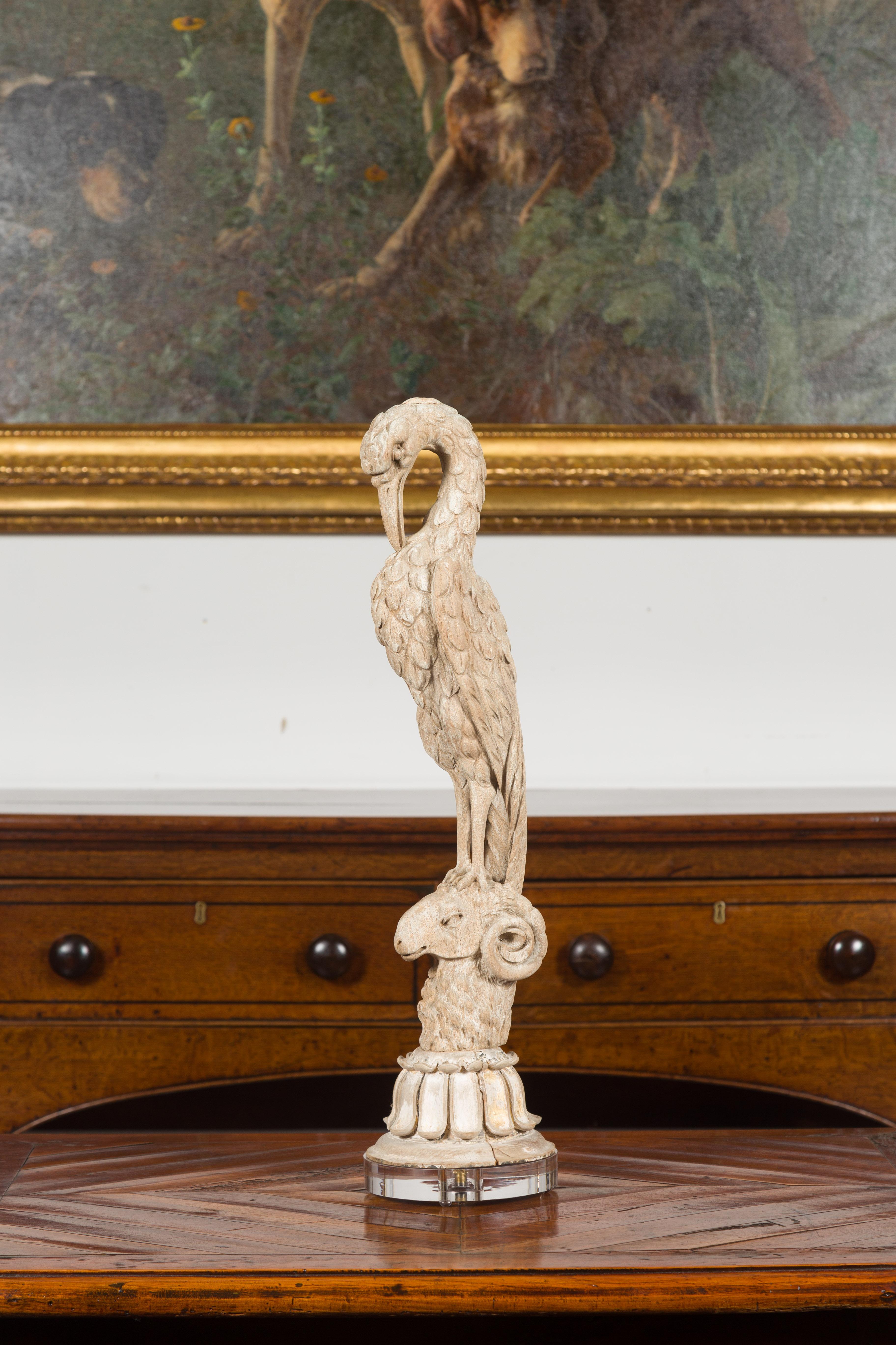 An Italian carved wooden bird on ram's head fragment from the 19th century, mounted on custom Lucite base. Created in Italy during the 19th century, this carved wooden fragment depicts a nicely detailed bird cleaning his own plumage and resting on a