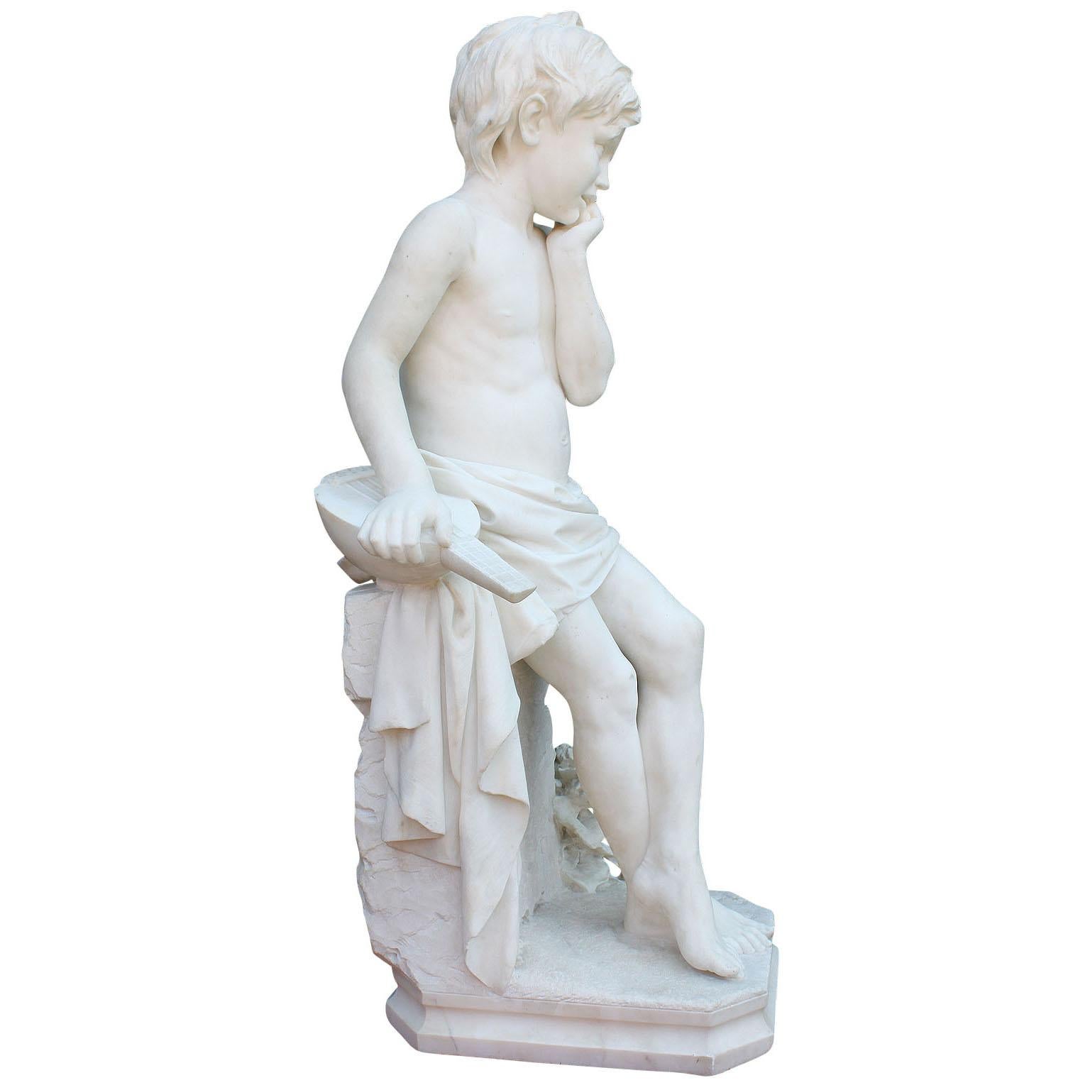 An Italian 19th century carved Carrara marble figure of a standing young boy with a mandolin. The standing figure of a young boy with crossed legs, semi-naked with a blanket around his waist, leaning on a rocky outcrop with wild plants at the base