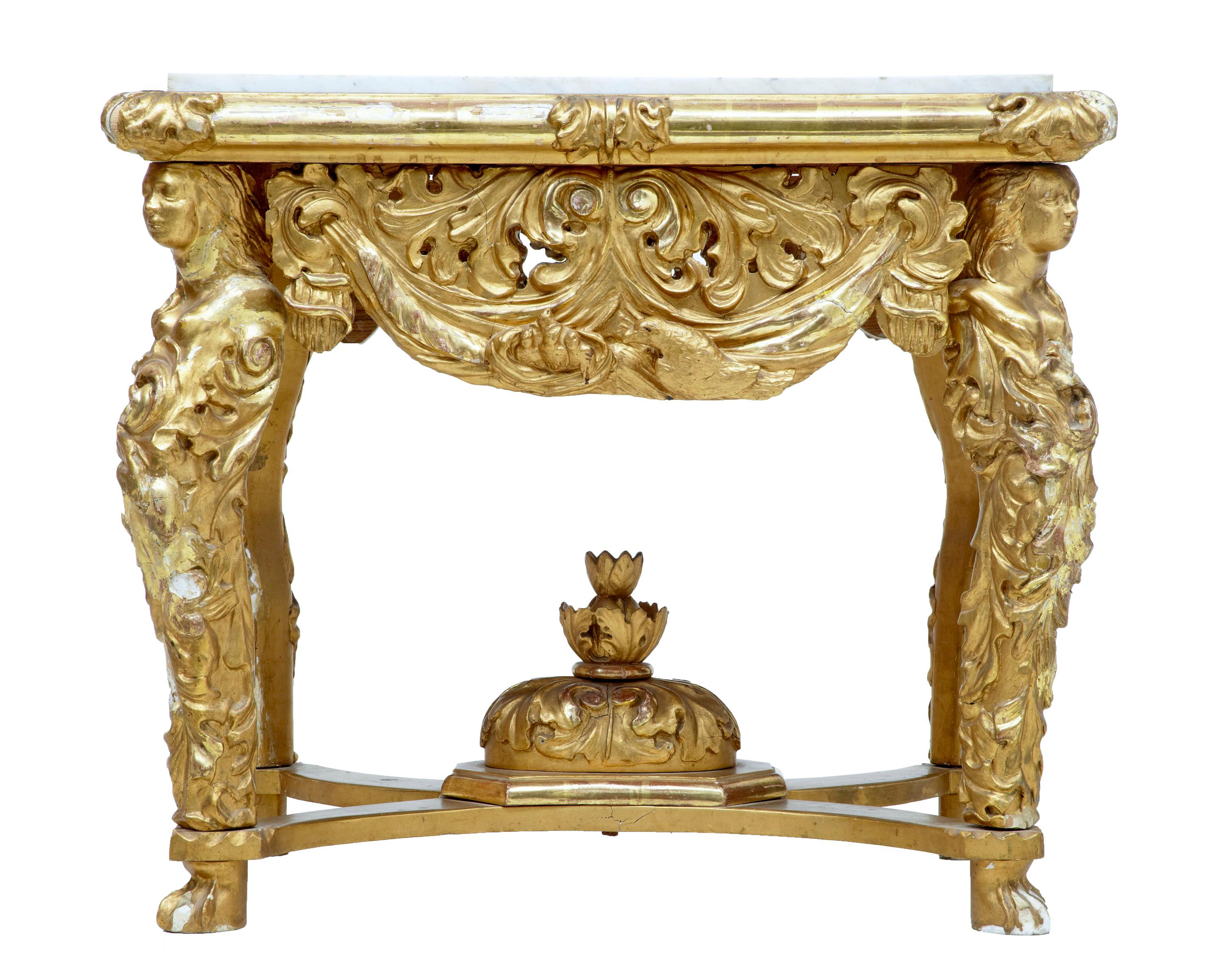 19th century carved wood and gilt center table, possibly Italian, circa 1850. Inset marble white grey veined top. Sides adorned with swags and scrolls. Each leg with carved female bust, with flowing acanthus leaves. Central decoration located in the