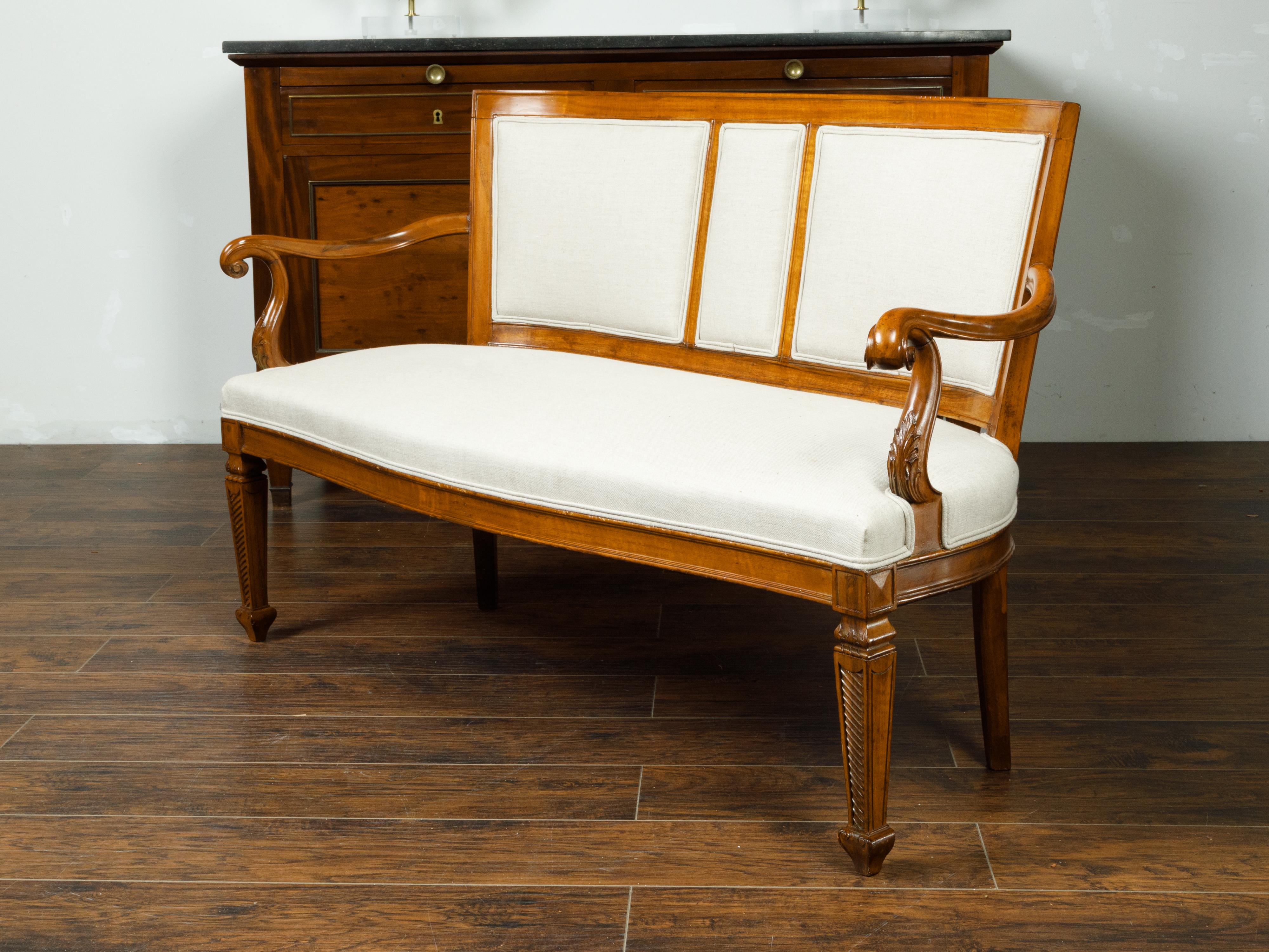 An Italian walnut settee from the 19th century, with curving back, scrolling arms and tapered feet. Created in Italy during the 19th century, this walnut settee features a curving back connected to two open arms with scrolling extremities and