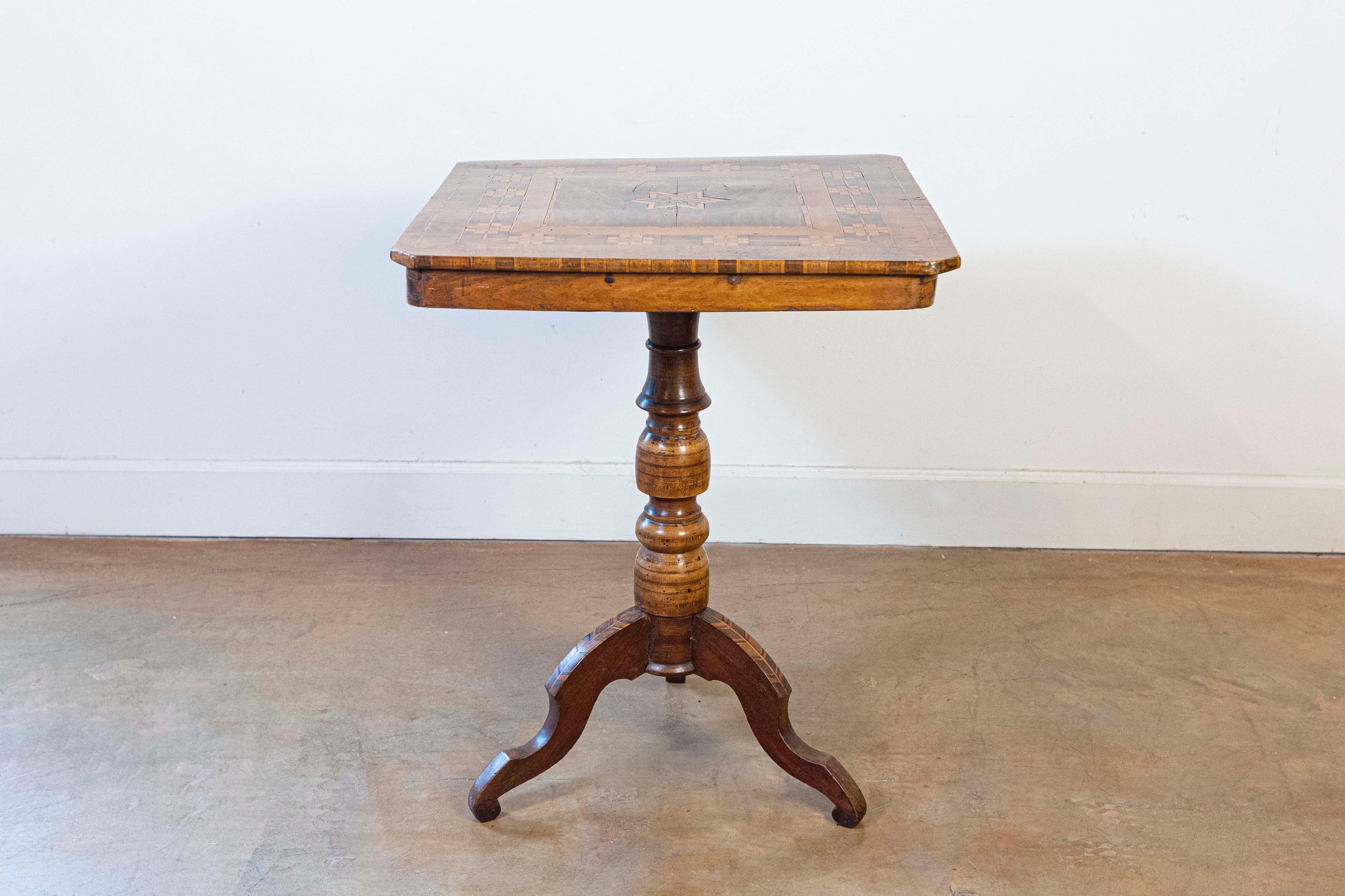 An Italian walnut, mahogany and European birch center table from the 19th century, with geometric and star shaped marquetry decor and turned pedestal. Created in Italy during the 19th century, this inlaid center pedestal table features a nearly