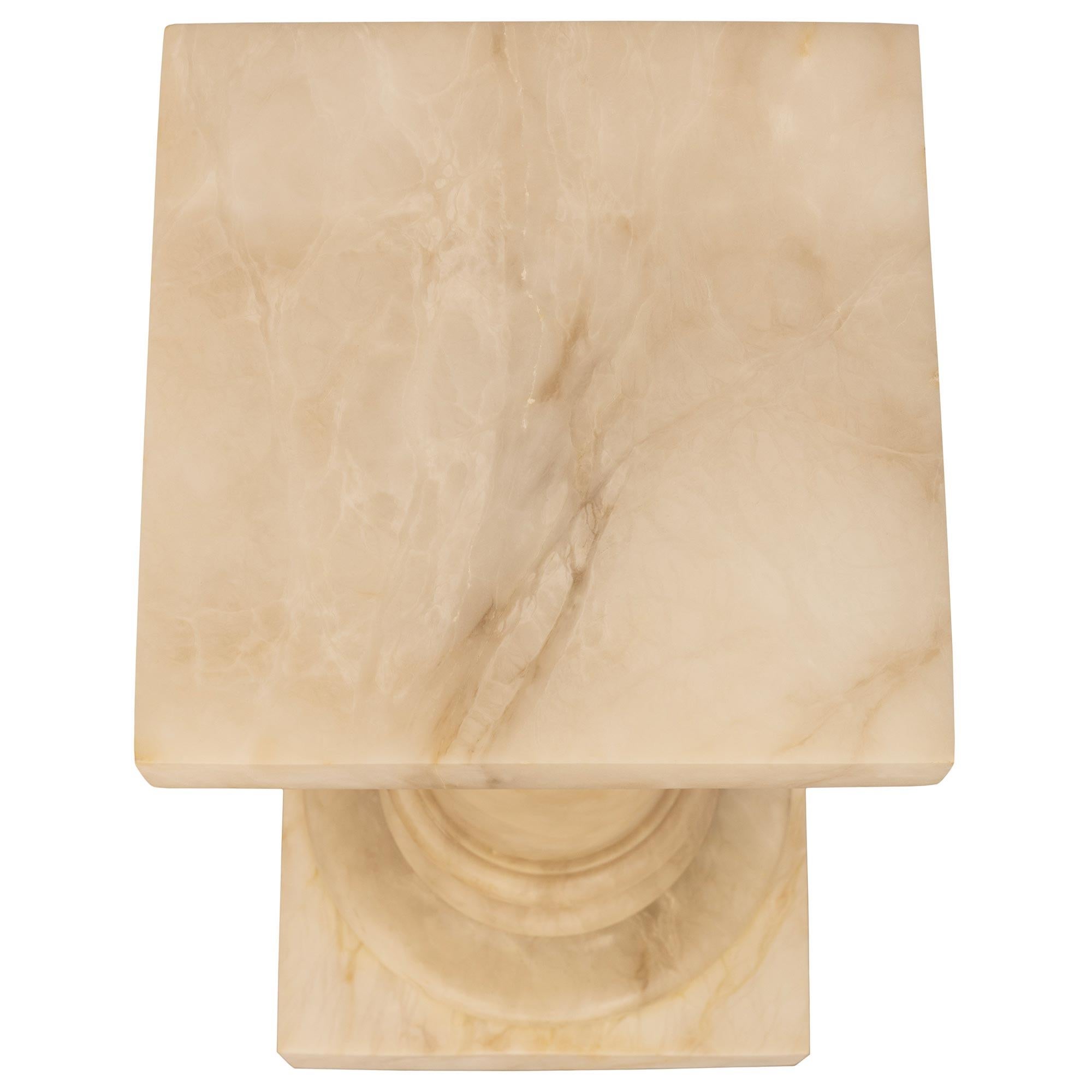 A handsome Italian 19th century cream colored Alabaster pedestal. The pedestal is raised by an impressive square block plinth below a mottled circular base. The circular column is below another circular mottled designed element all below the top