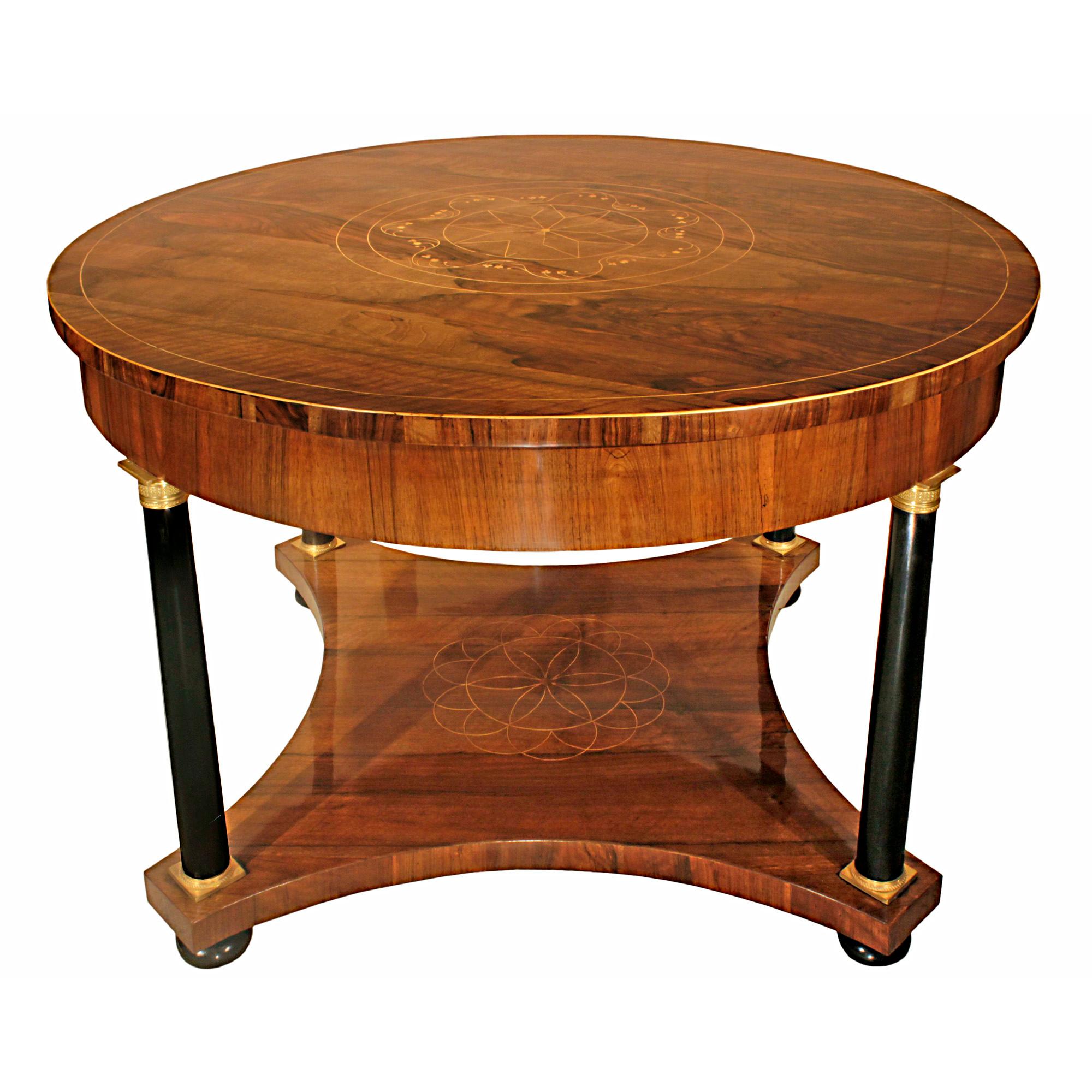 A magnificent Italian 19th century round ormolu mounted ebonized fruitwood and crouch mahogany center table with cherry wood inlay. The table is raised by four ball feet below the concave stretcher with a cherry wood inlaid radial design of the seed