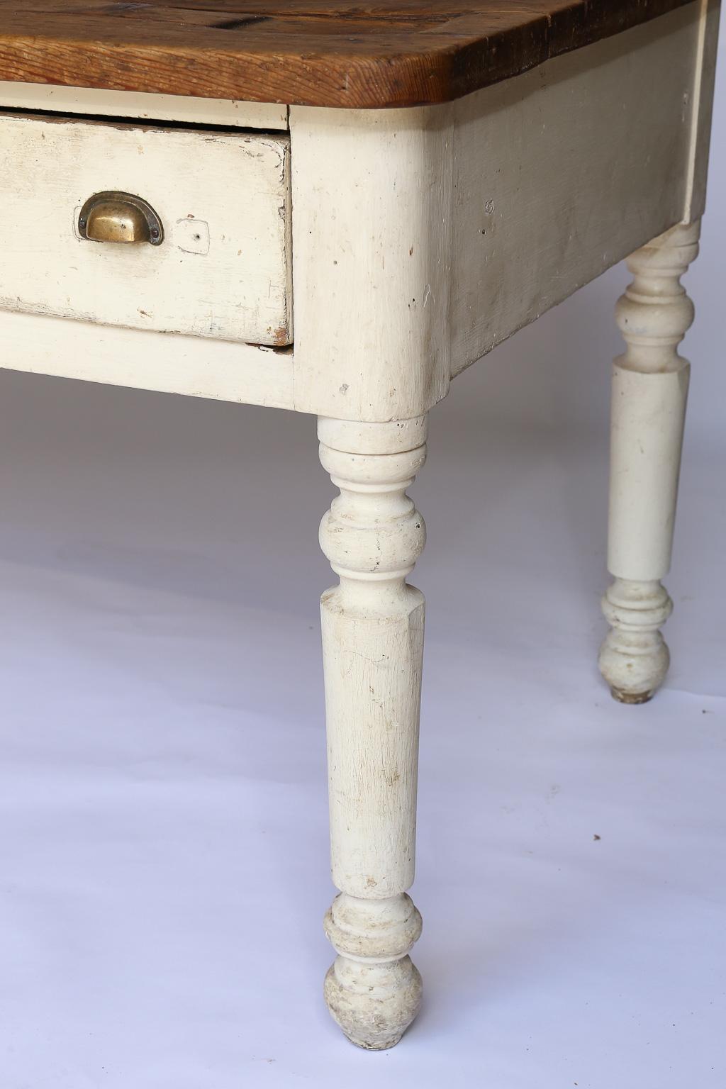 Originally used by an Italian tailor or seamstress this lovely drapers table would be beautiful as a kitchen island, console or entryway piece. The base of the table, painted a creamy white, has turned legs and two drawers with brass pulls, while