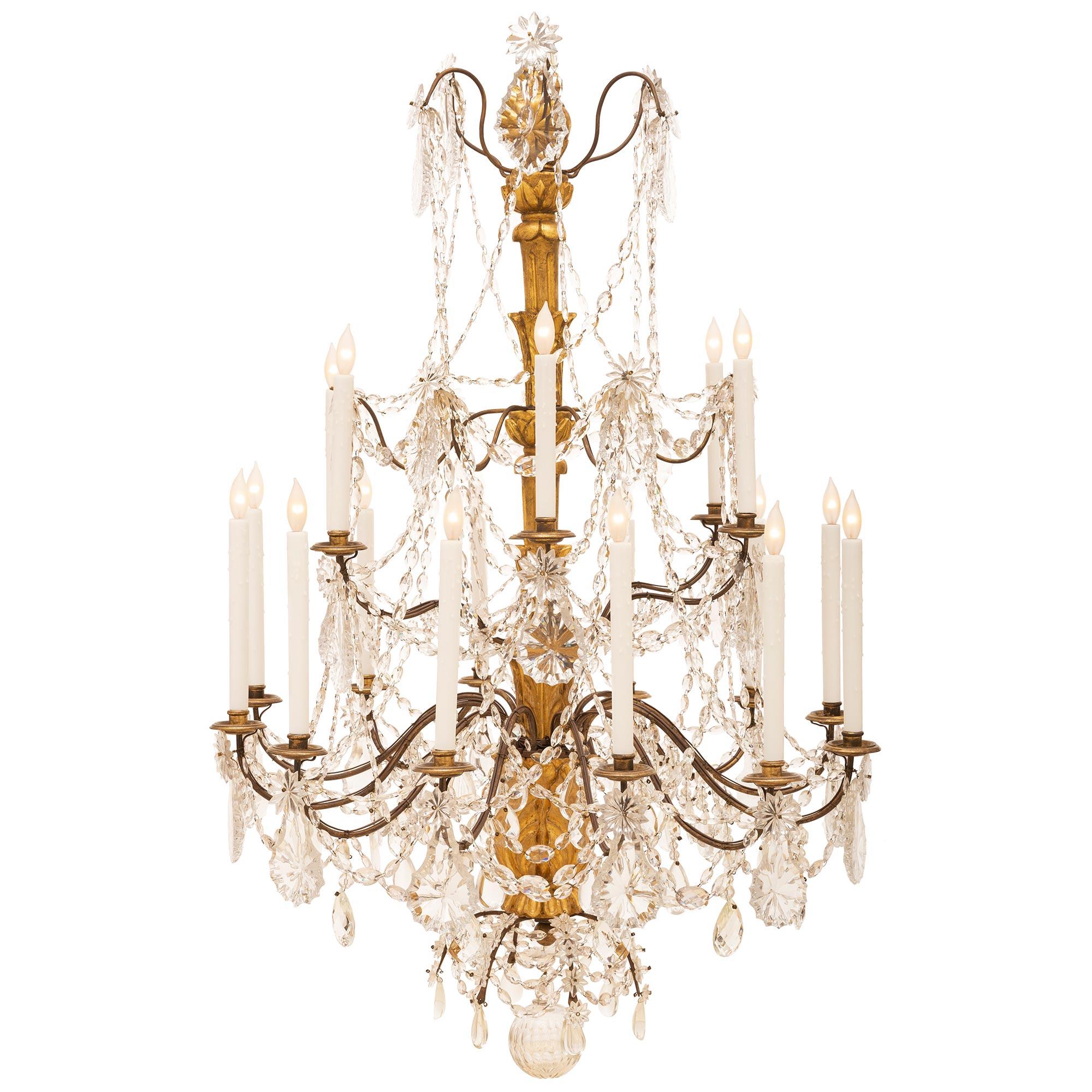 A stunning and unique Italian 19th century eighteen light giltwood, patinated bronze and crystal chandelier from Northern Italy. The chandelier has an elegant hand blown cut crystal bottom sphere surrounded by a lovely spray of tear drop shaped cut