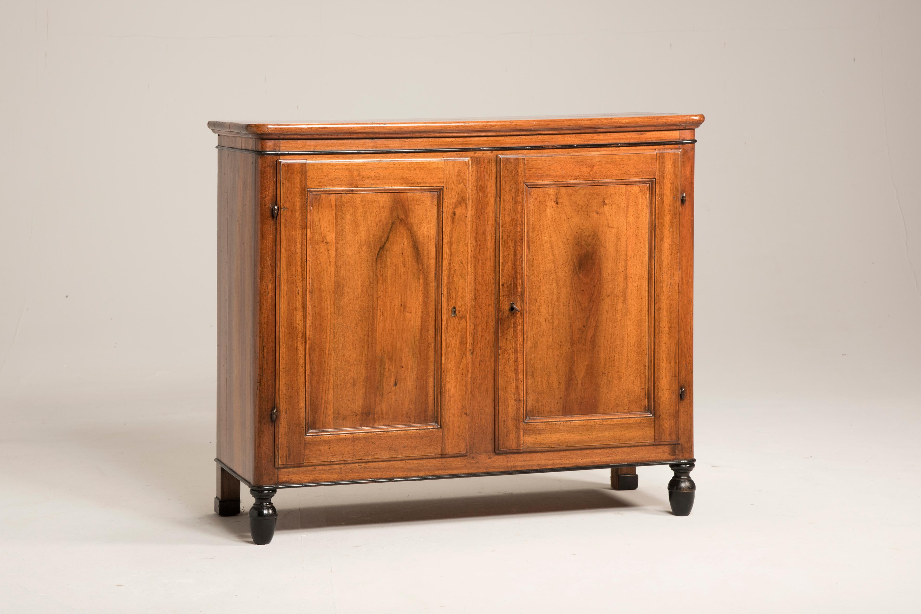 Italian 19th century Empire walnut wood two-door credenza. Rounded edges and black legs. From Veneto, a north region of Italy from early 19th century. The sideboard features two doors and one big storage space with one adjustable shelf. We have
