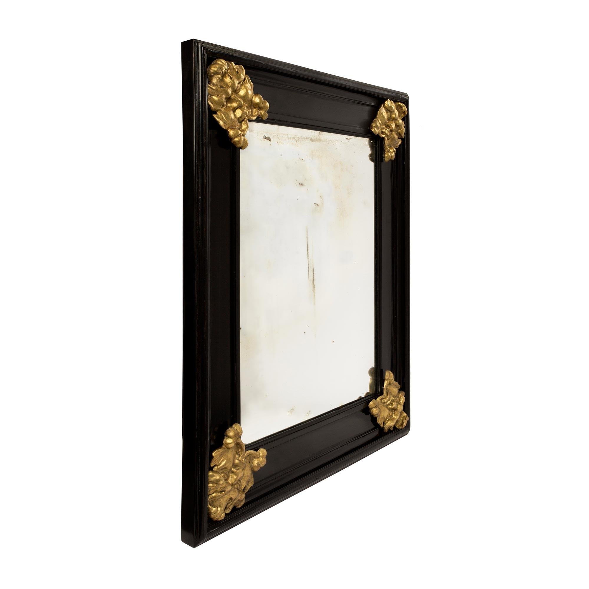 A handsome Italian 19th century Florentine ebony and giltwood mirror. The original mirror plate is framed within a thick mottled ebony frame with richly carved giltwood satyrs at each corner.

  