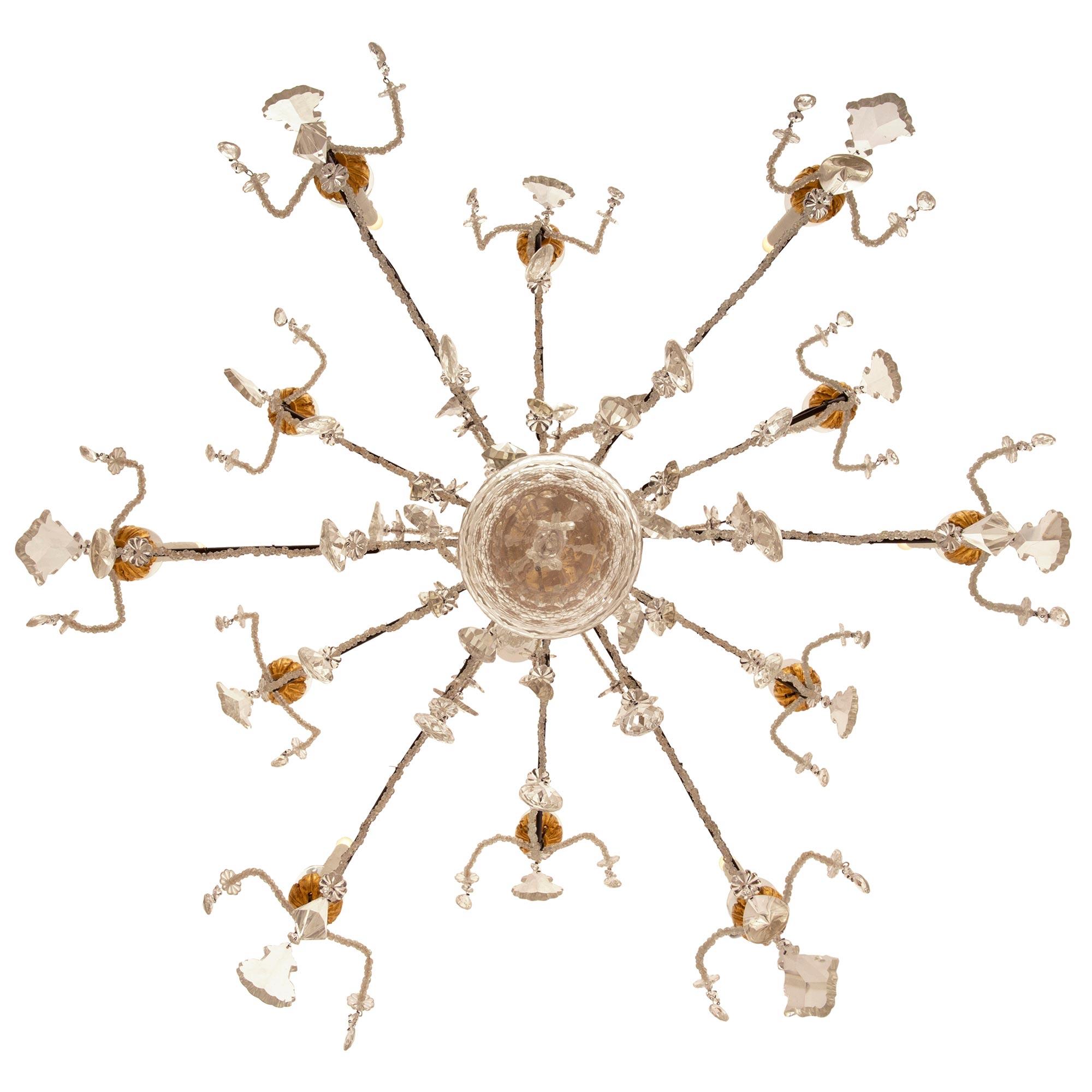 A stunning and extremely decorative Italian mid 19th century Genovese st. giltwood, wrought iron, and crystal chandelier. The twelve arm chandelier is centered by a beautiful bottom crystal ball with a lovely honeycomb like design below fine cut
