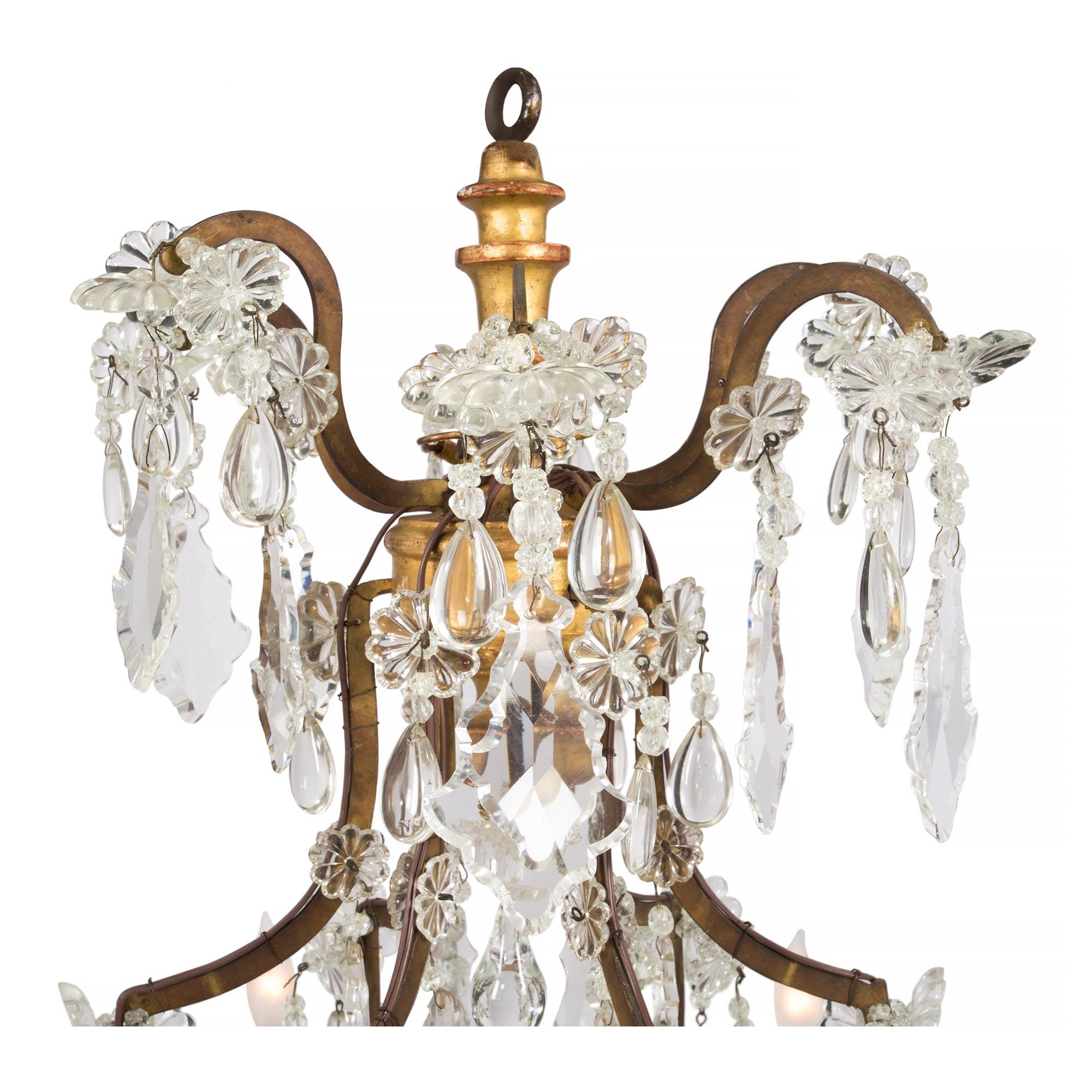 A wonderful Italian 19th century giltwood and crystal seven light chandelier. The six metal scrolled arms end in giltwood bobeches and are joined by draping crystal garlands, centered by a single light. Decorated throughout with kite and teardrop