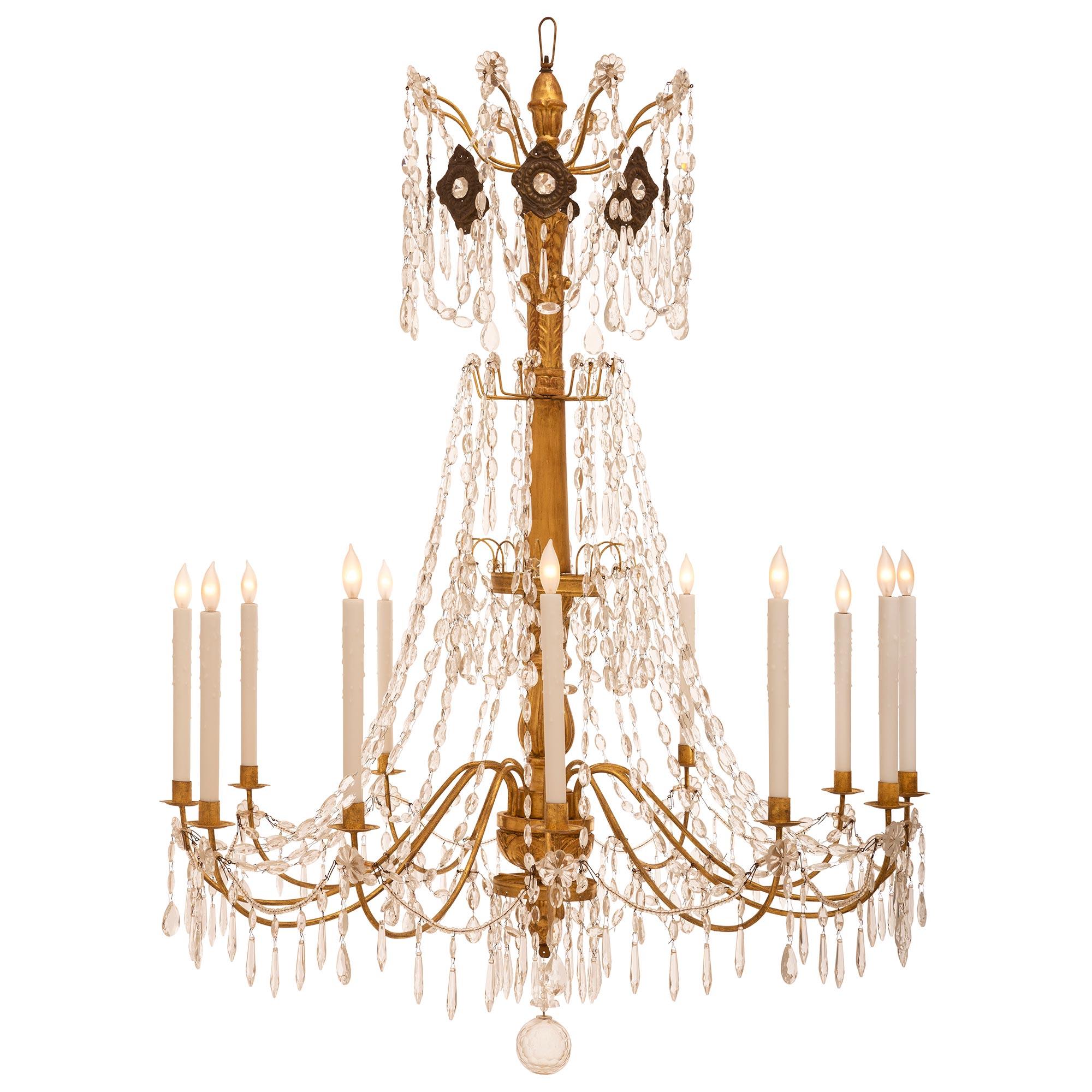 An impressive 19th century Italian giltwood and gold leaf on metal chandelier with crystal and glass garlands. The twelve scrolled gilt metal arms are decorated by crystal drops topped by rosettes and are joined by glass beads accented by crystal