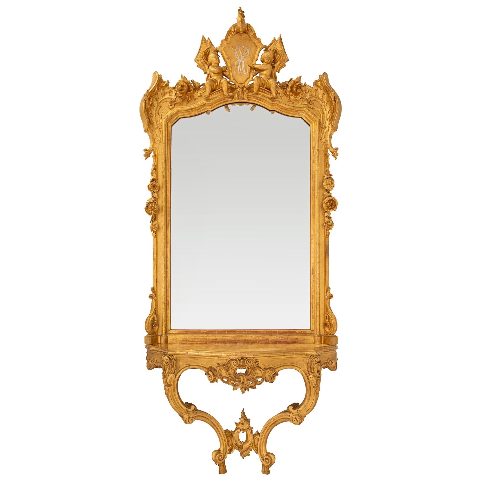 Une spectaculaire console et un miroir en bois doré italien du 19ème siècle. La console repose sur des pieds à volutes en 