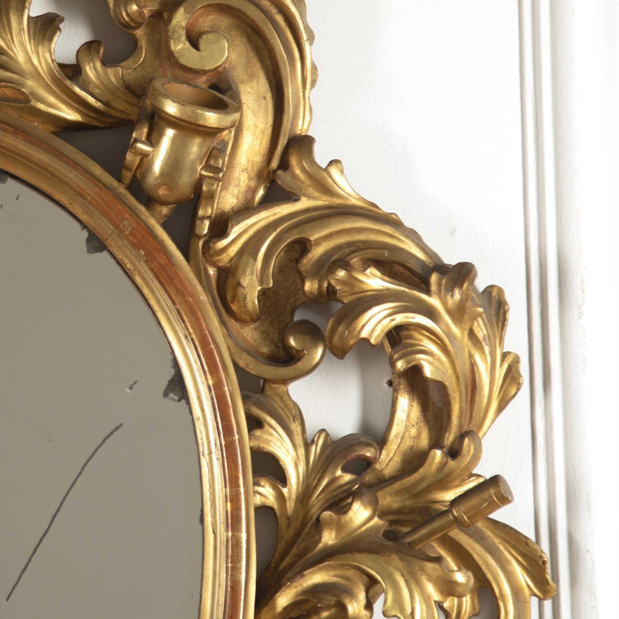 Florentine 19th century giltwood mirror.
This fantastic mirror is boldly carved with military trophies. It has its original oval mercury plate within a moulded frame that is surrounded by extravagant foliate carving.
The carvings throughout the