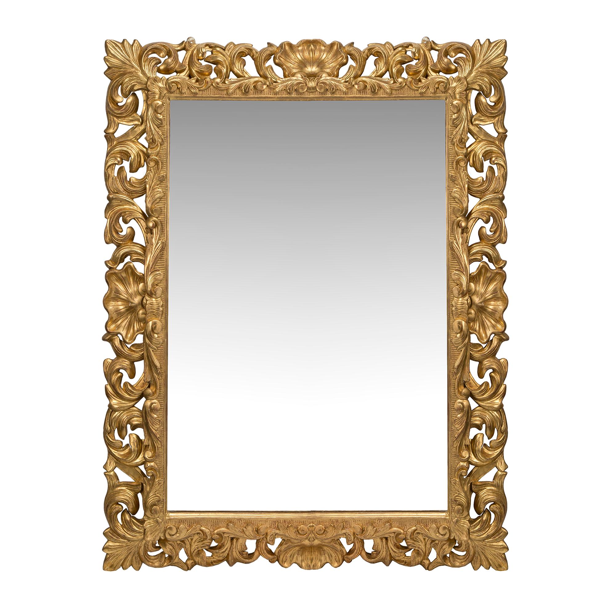 A stunning Italian 19th century giltwood mirror from Florence. The finely carved pierced frame is centered at each side with a large seashell cabochon and accented at each corner with large acanthus leaves. The wonderful scrolled foliate continues