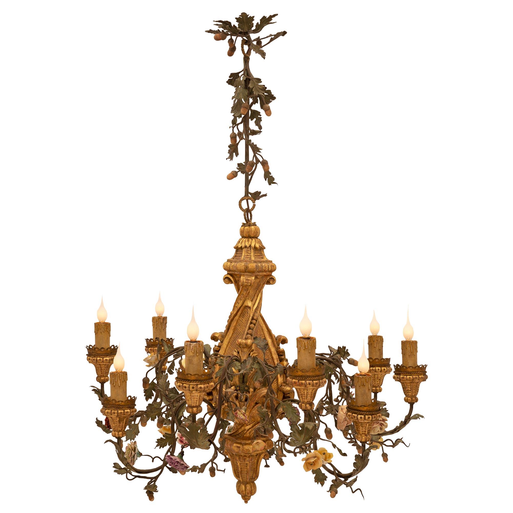 A beautiful and most decorative Italian 19th century giltwood, porcelain, and patinated iron chandelier. The nine arm chandelier is centered by a central charming richly carved inverted giltwood foliate finial below lovely scrolled movements. At the