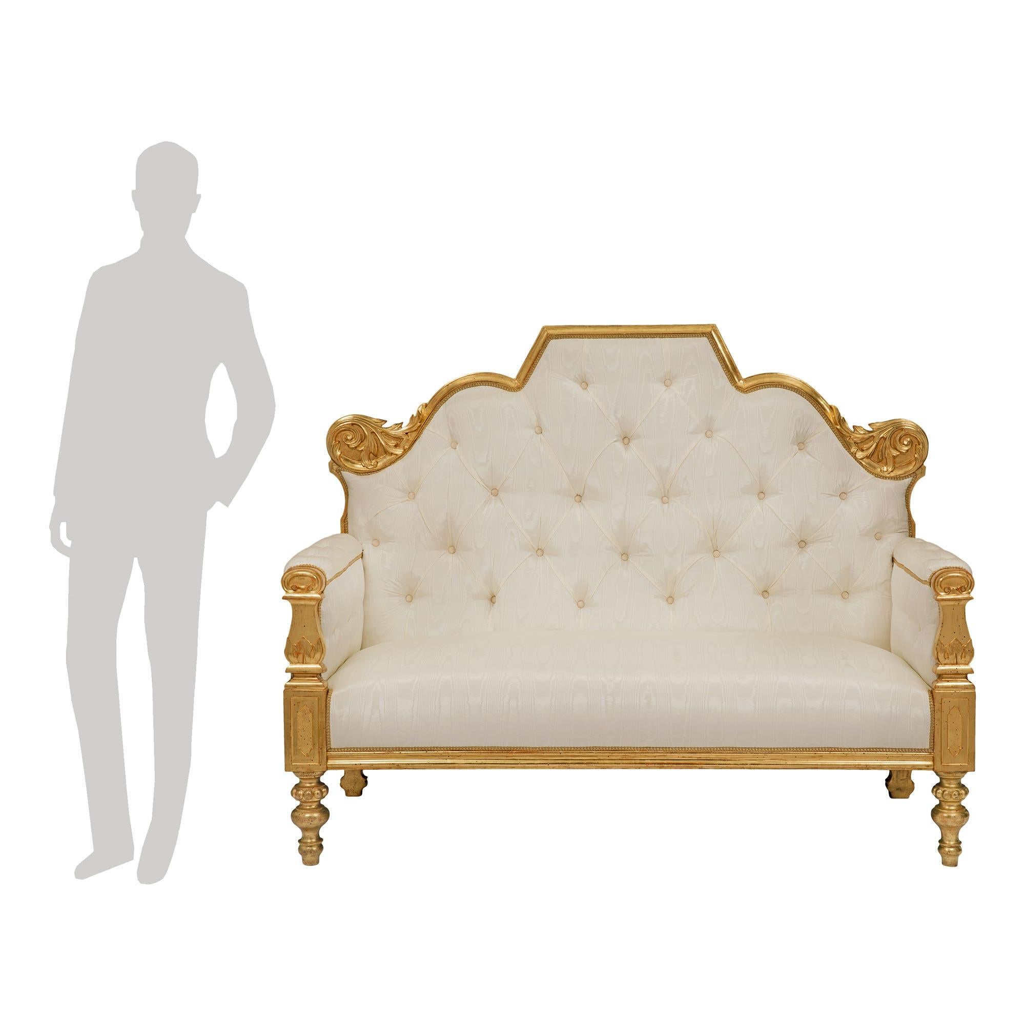 A striking and most elegant Italian 19th century giltwood settee. The settee is raised by fine topie shaped legs with a lovely beaded design below carved recessed block reserves. The straight frieze displays a mottled design while the cushioned arm