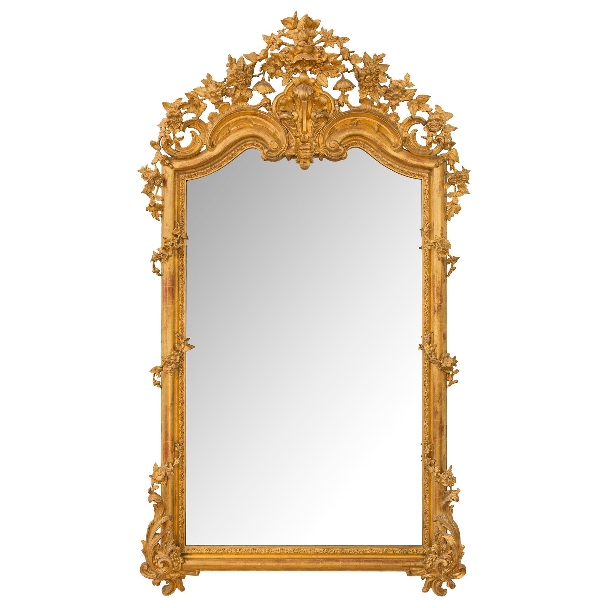 A stunning large scale Italian mid 19th century Louis XVI st. giltwood mirror. The mirror retains its original mirror plate set within a beautiful finely carved mottled foliate band with a delicate and most decorative lattice background. At each