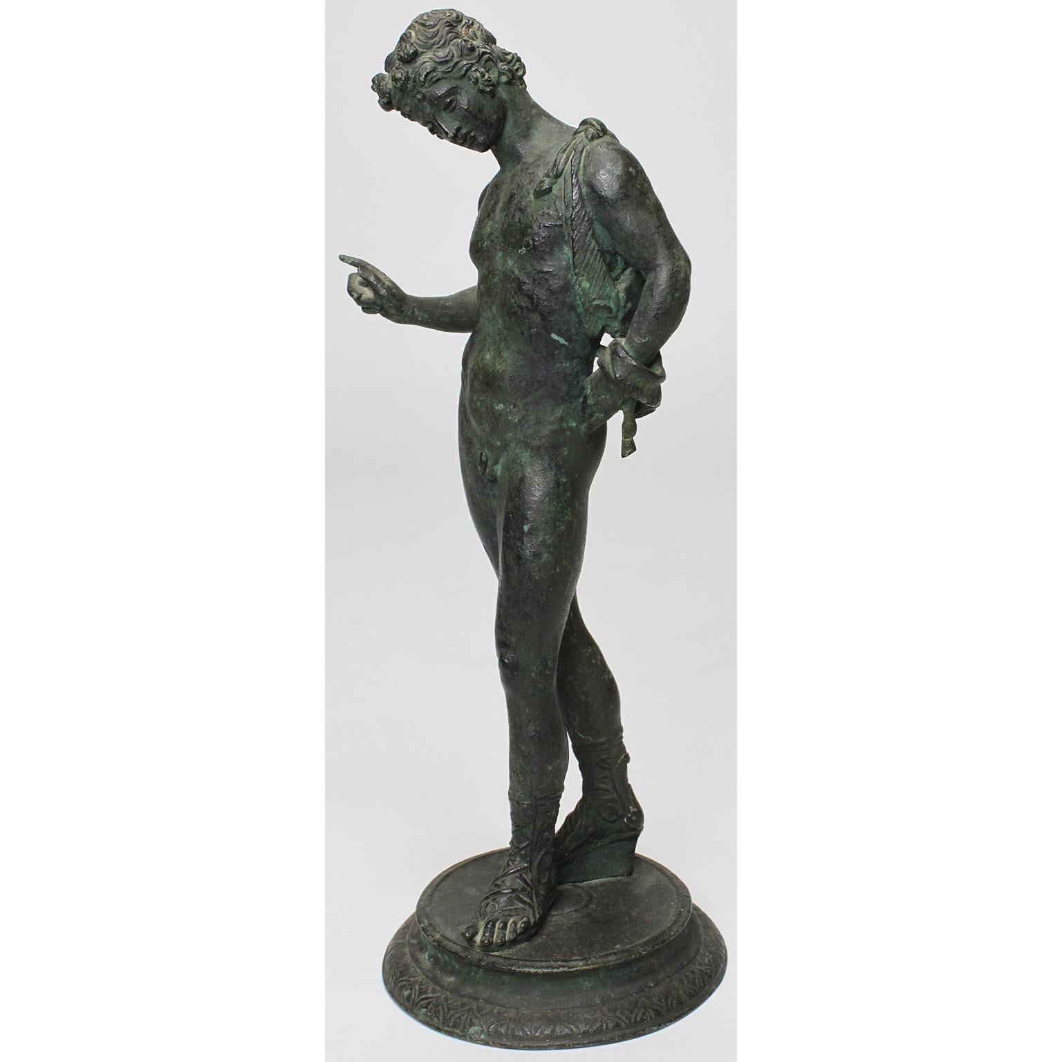 An Italian 19th century grand tour - Greco Roman bronze sculpture of Narcissus, after the original sculpture excavated in 1862 at Pompeii. The green patinated bronze figure of slender standing and posing nude man wearing Roman sandals, circa
