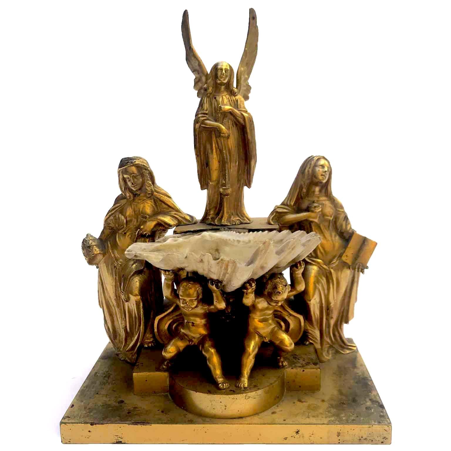 From Italy a stunning gilt bronze holy water font dating back to the first half of 19th century. An ormolu group sculpture depicting an unusual composition: on a stepped rectangular base two cherubs holding an original shell surmounted by a winged