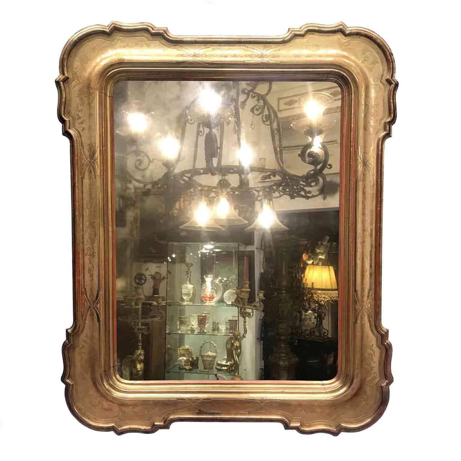 Large mid 19th century carved and golden leaf gilded wooden mirror with antique original dark mercury glass, in a whole plate.
This shaped Louis Philippe Italian frame is finely carved with bulino and punched ground, finely decorated with vegetal