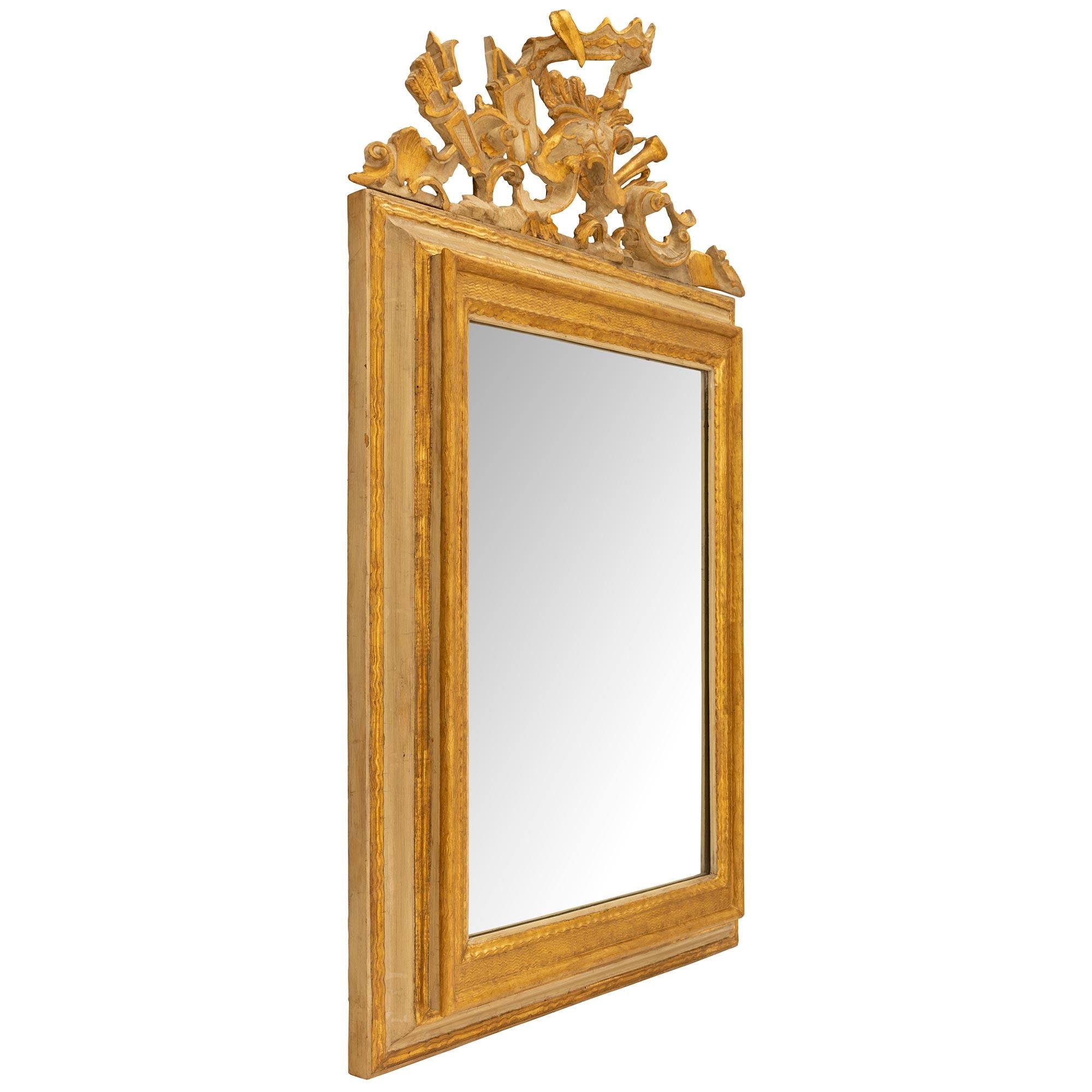 A striking Italian 19th century Louis XIV st. patinated and gilt mirror. This mirror has a mottled frame with gilt borders and fitted with the original mirror plate. At the pierced top crown are patinated festive designs with gilt borders of